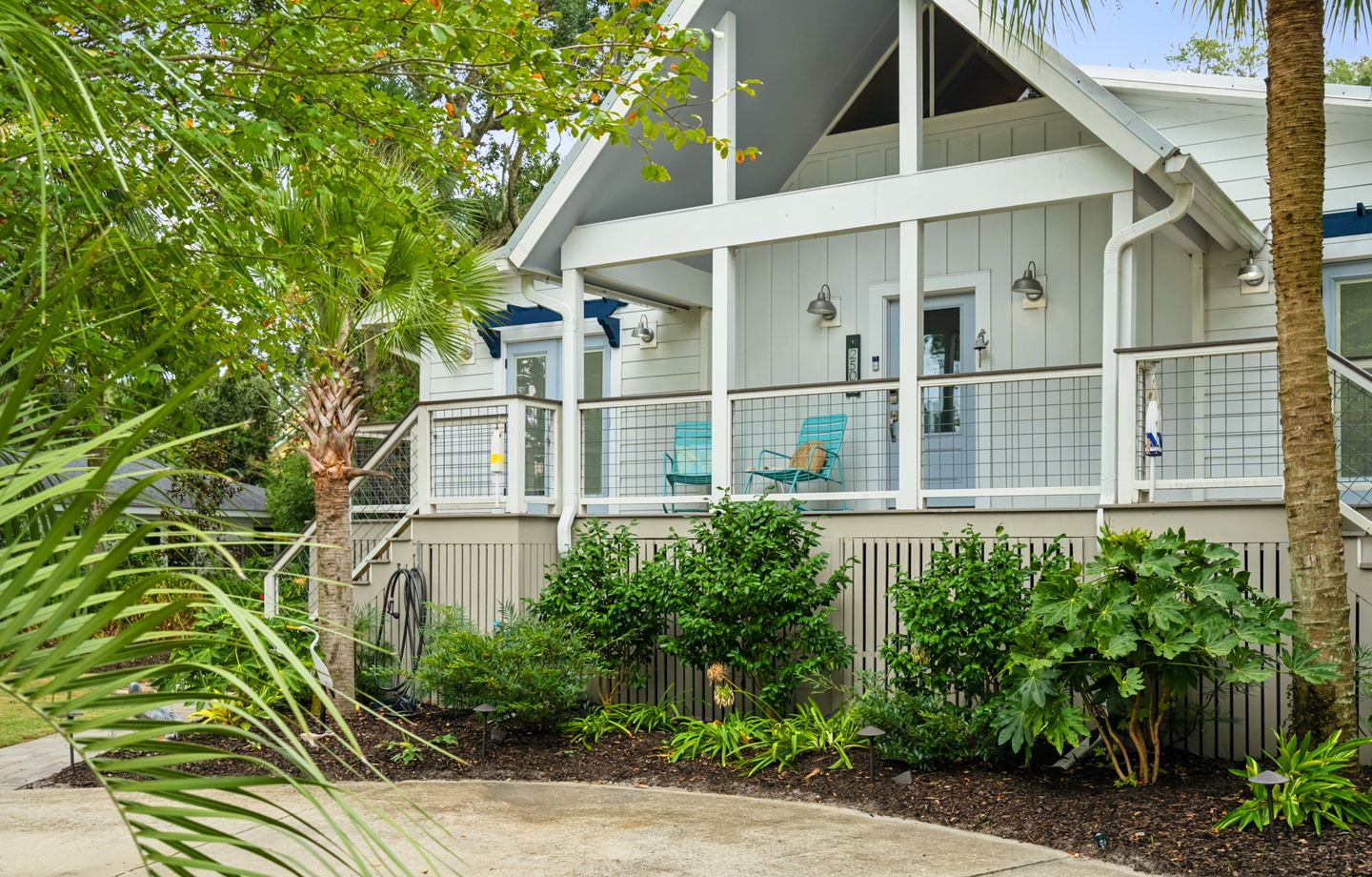 Charming coastal-style home nestled among tropical palms and lush greenery. An elevated porch with inviting seating welcomes you to this private retreat where island living meets modern comfort.