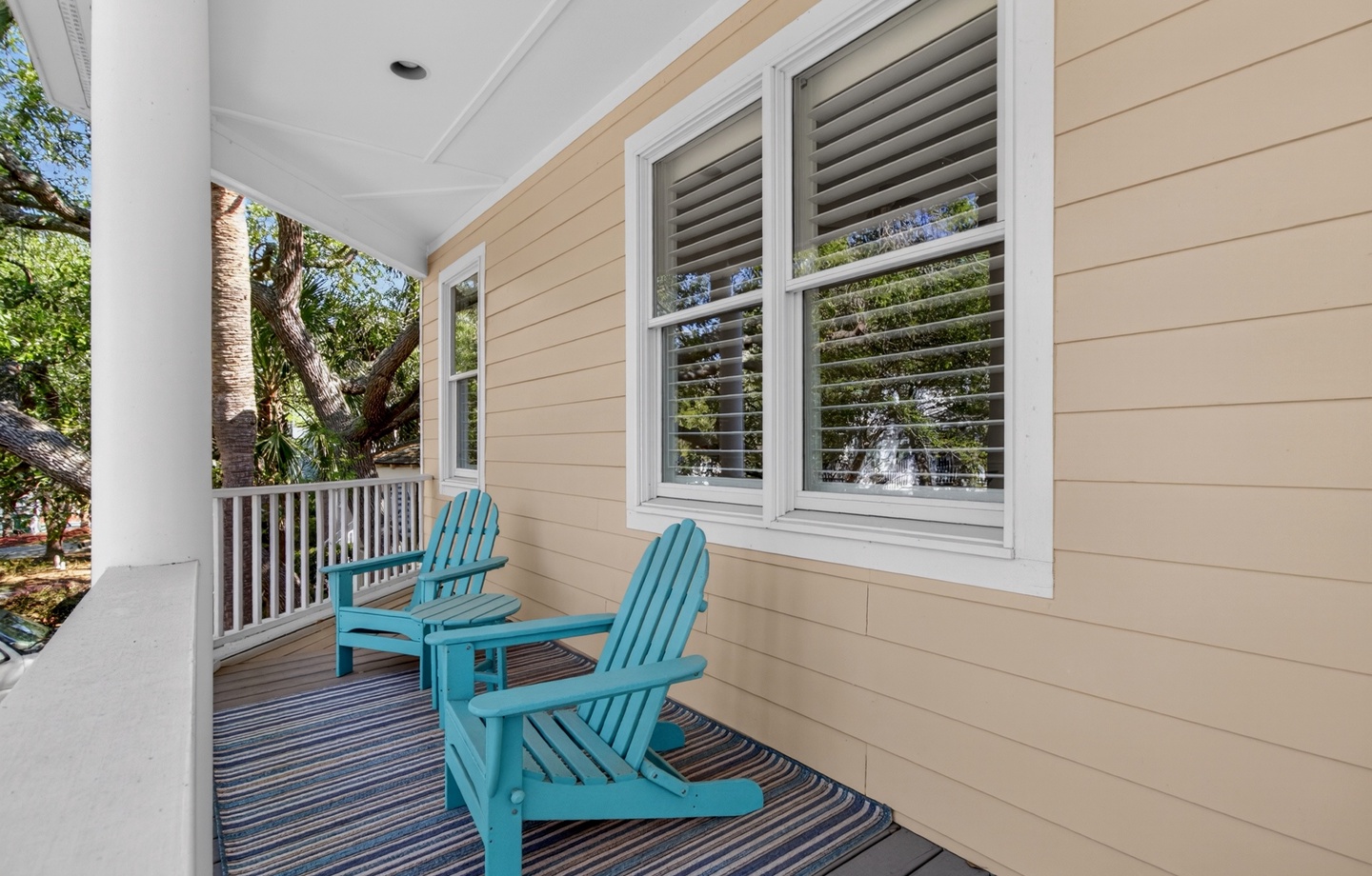 Step onto your private covered porch and sink into vibrant turquoise Adirondack chairs, where you'll sip morning coffee surrounded by lush tropical greenery.