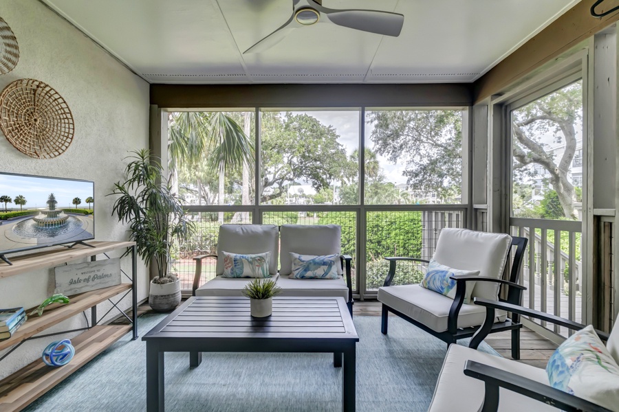 Relax on your screened porch with ceiling fan and comfortable seating while overlooking peaceful trees and greenery outside.