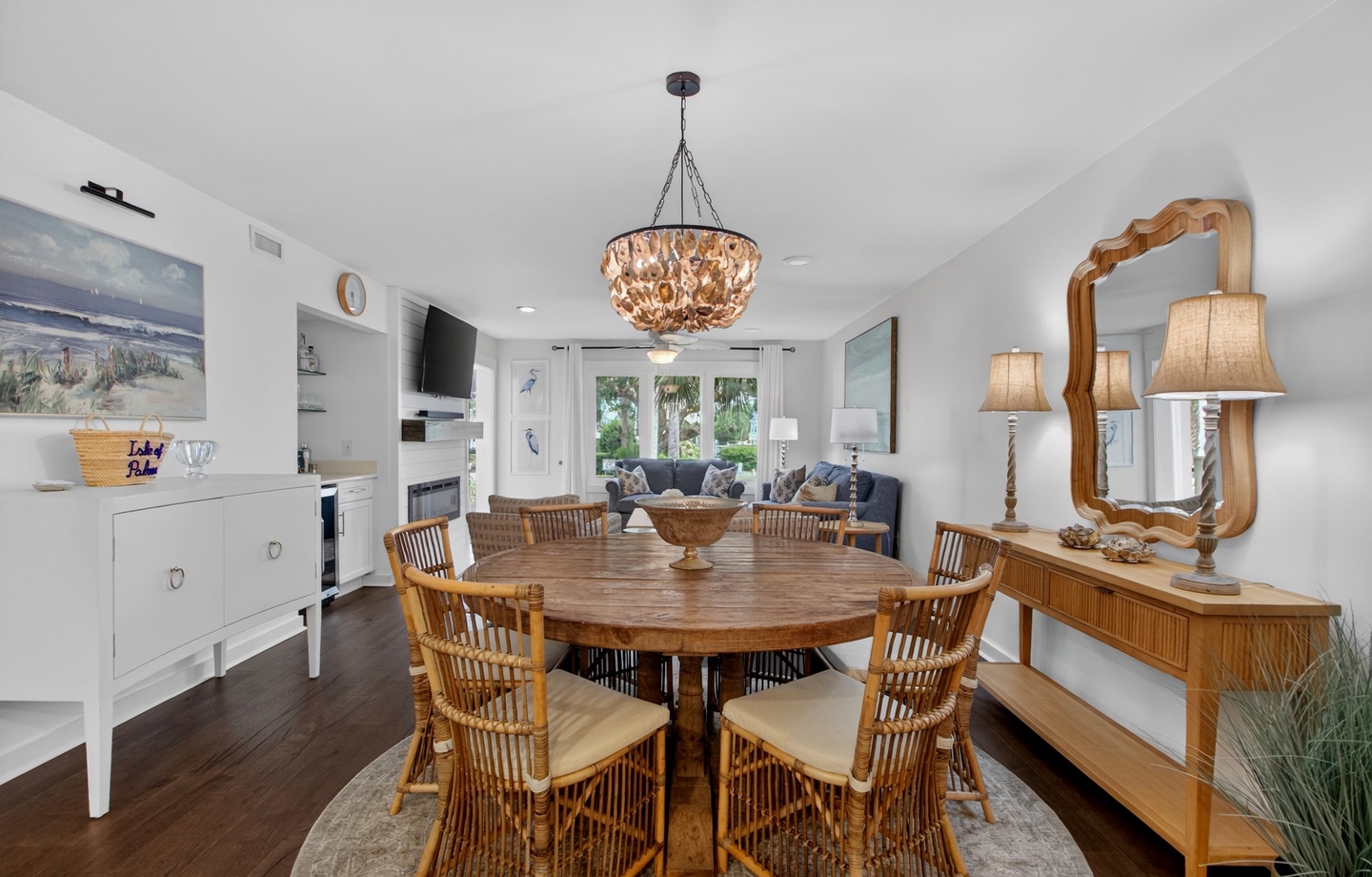 Gather around the dining table beneath a coastal chandelier, with comfortable seating for your group and an open flow to the bright living area beyond.