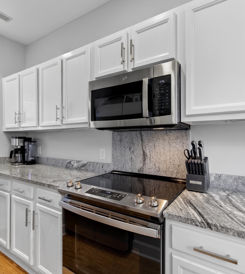 Cook your favorite meals in this sleek kitchen with granite countertops, stainless steel appliances, and crisp white cabinets.