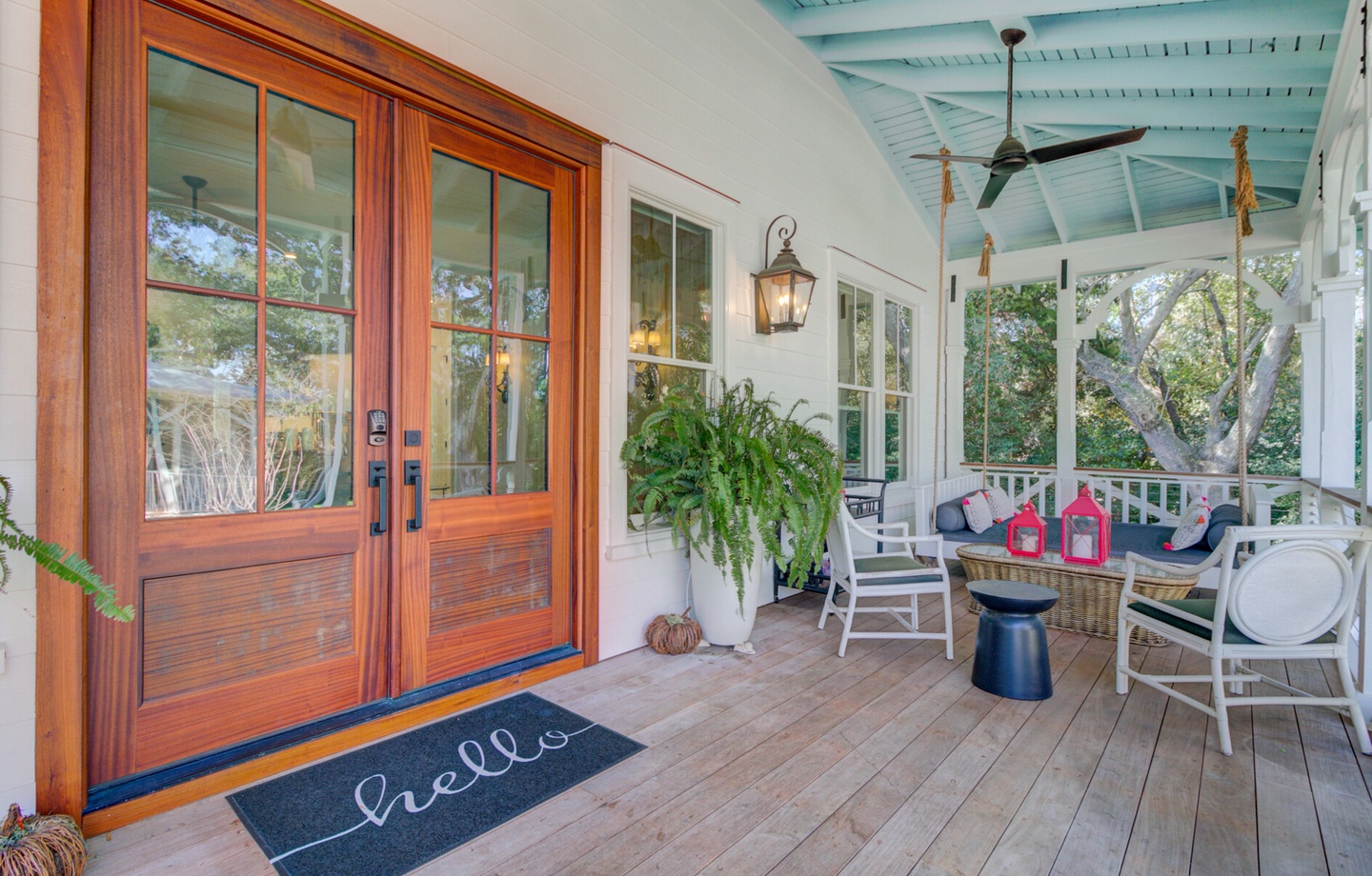 Welcome to your charming front porch where you can sip morning coffee surrounded by lush greenery and coastal charm.
