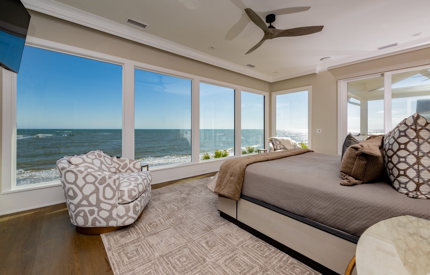 - Wake up to sweeping ocean vistas from a serene, window wrapped bedroom - Soft linens, a plush armchair, and layered textures enhance comfort and warmth - Ideal spot to unwind after beach days or sip morning coffee with a view