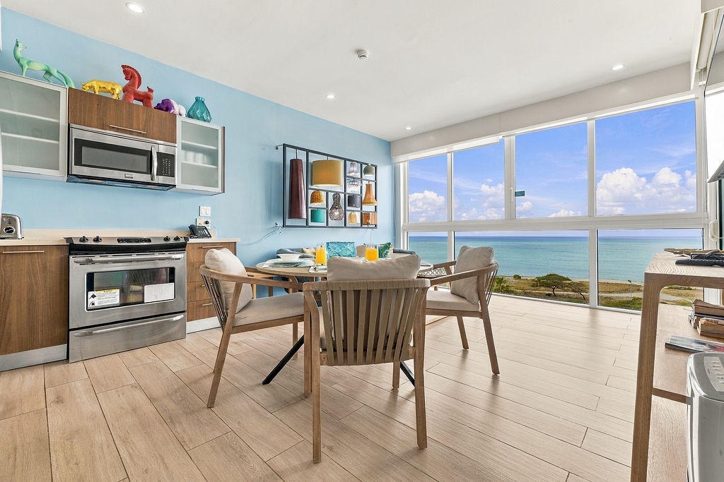 Start your day at this bright dining table with stunning ocean views stretching before you. Floor-to-ceiling windows frame the turquoise coastline while you enjoy morning coffee in this cheerful space.
