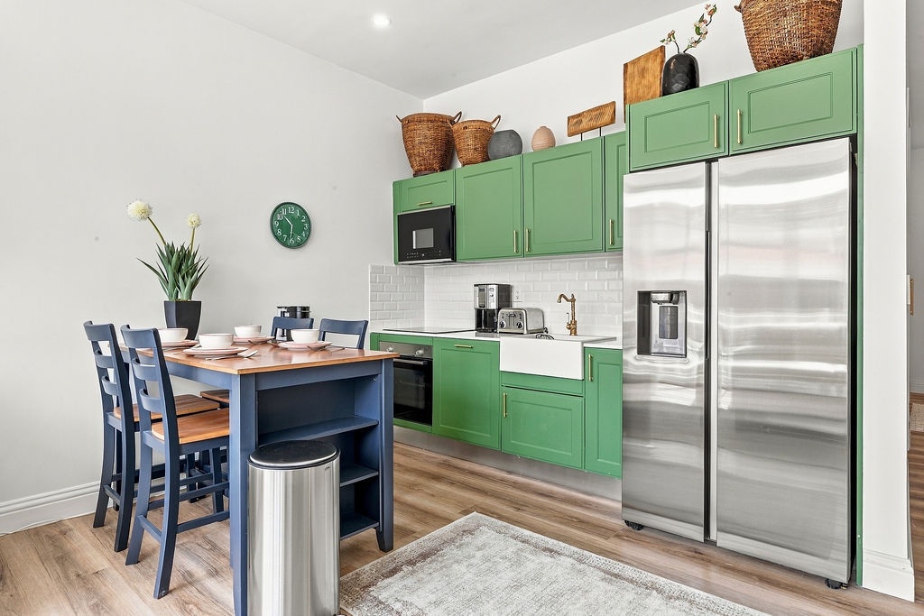 Picture yourself preparing meals in this bright, cheerful kitchen with charming green cabinetry, stainless steel appliances, and a cozy dining spot right at your fingertips.