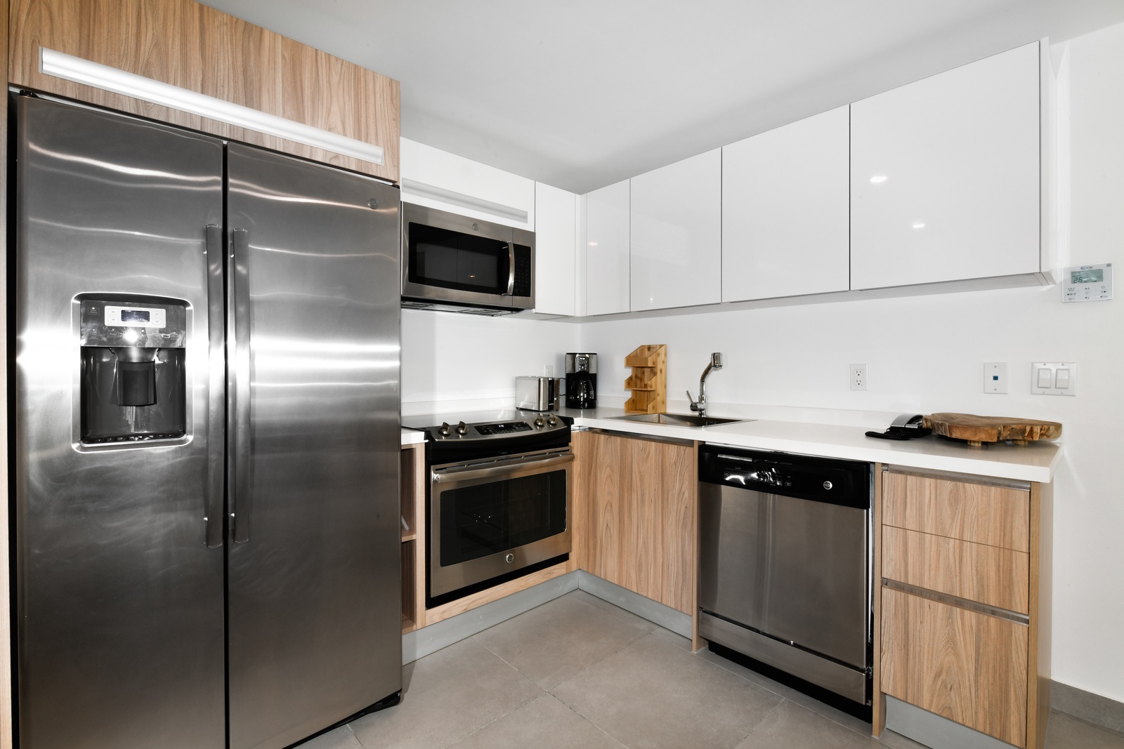 Your modern kitchen features sleek stainless steel appliances, bright white counters, and warm wood-grain cabinetry—perfect for preparing meals in comfort and style.