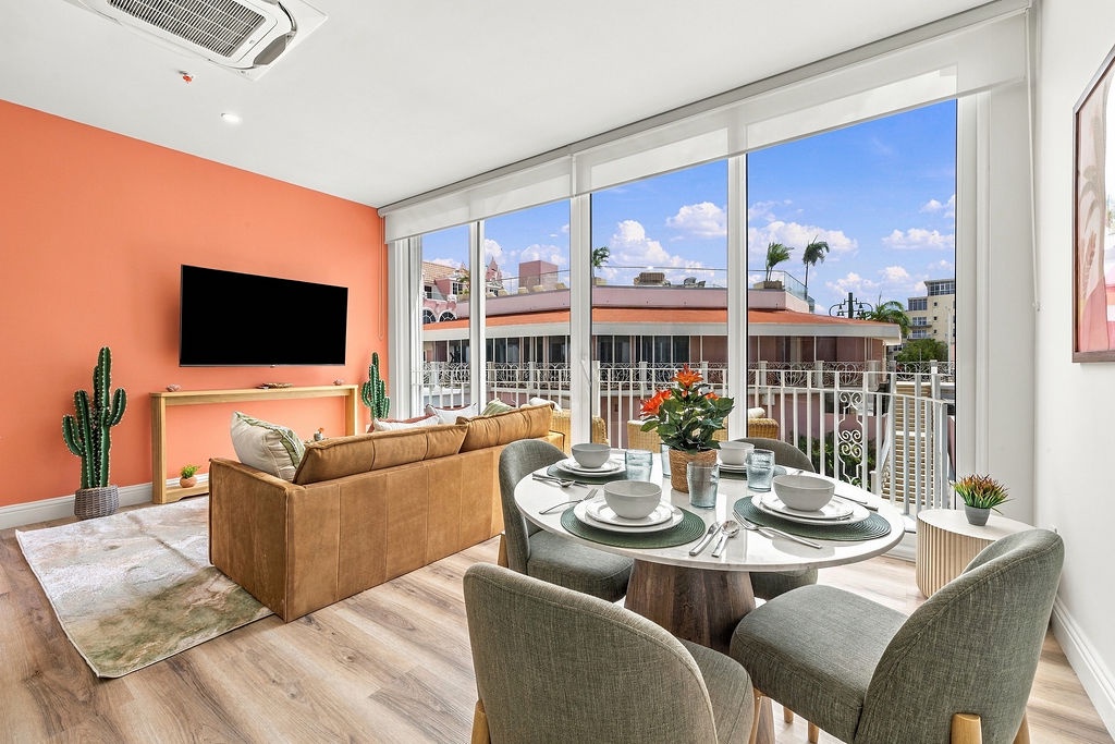 Sink into the caramel-toned sofa and soak in the sunlit sky and city rooftops through floor-to-ceiling windows. The dining table awaits your morning coffee or evening meal, all framed by tropical breezes and effortless style.