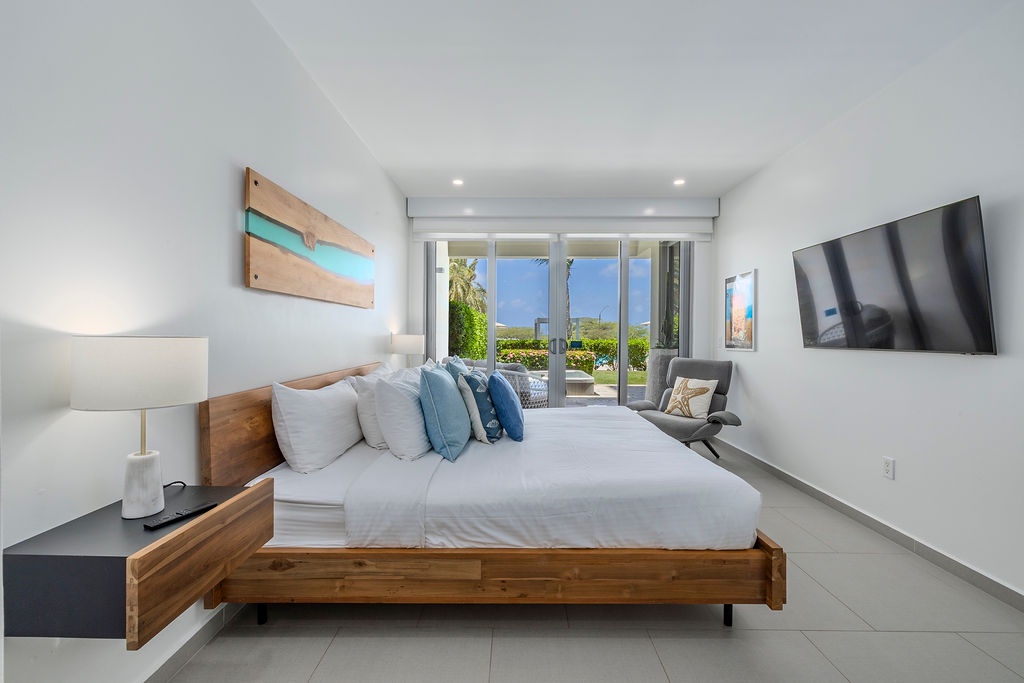Wake to ocean views and gentle breezes flowing through your serene coastal retreat. Your peaceful bedroom features elegant modern furnishings and direct terrace access for morning coffee overlooking paradise.