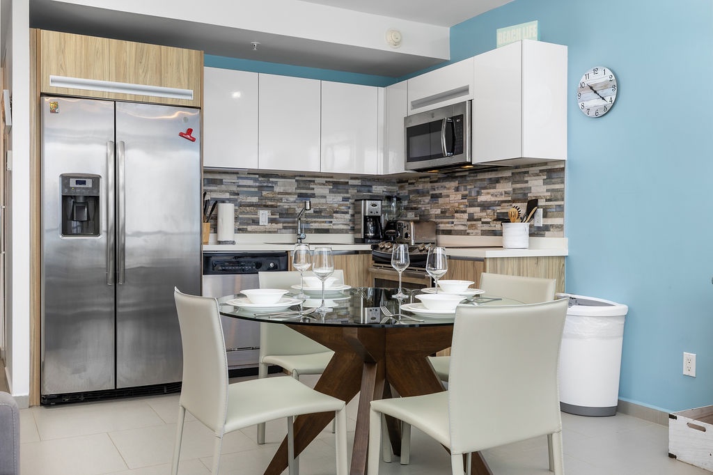 Gather around your sleek dining table in this modern, fully-equipped kitchen, where bright blue accents and thoughtful design create an inviting space for cooking, sharing meals, and making memories together.
