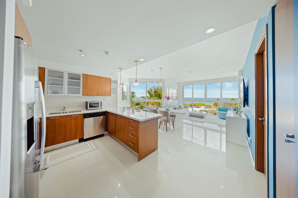 Your sleek kitchen flows seamlessly into the bright living space, where floor-to-ceiling windows frame stunning ocean views.