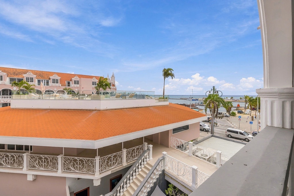 A charming coastal town unfolds before you, with terracotta rooftops, palm-lined streets, and the sea stretching beyond—your ideal escape awaits.