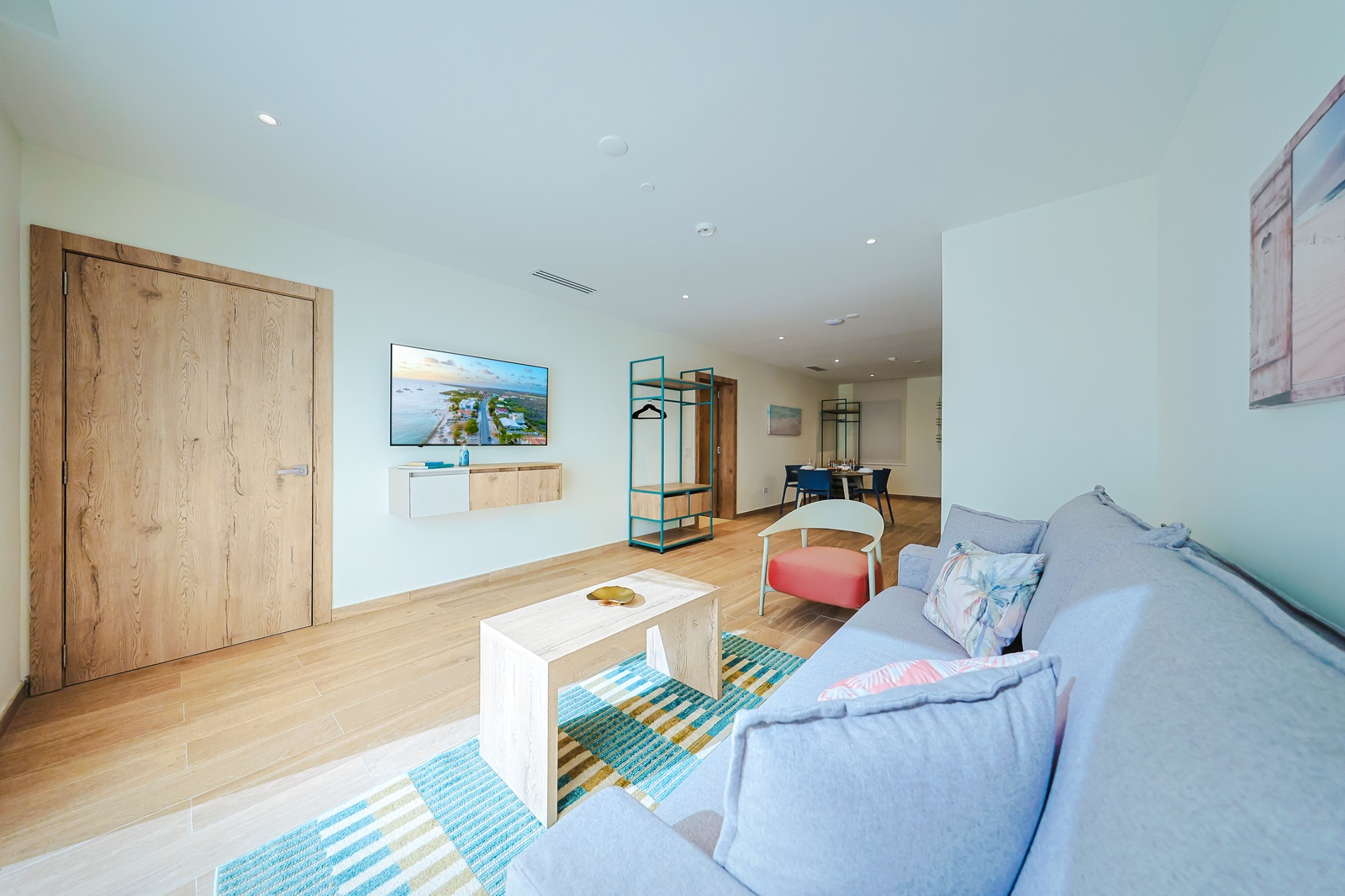 Unwind in your spacious living area with soft seating, warm wood floors, and coastal artwork that sets a relaxed, beachy vibe—perfect for cozy evenings or lazy mornings.