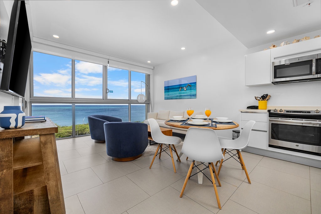 Picture yourself sipping morning coffee at this bright, modern dining space where ocean views stretch endlessly beyond floor-to-ceiling windows—a serene escape where every meal feels like a coastal retreat.