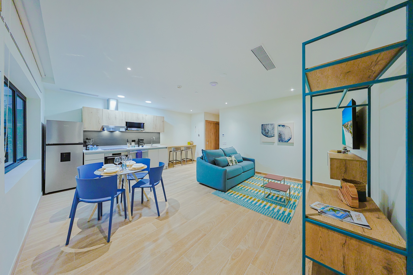 Step into your bright, open living space where vibrant blue seating and a fully-equipped kitchen invite you to relax and enjoy effortless vacation living.