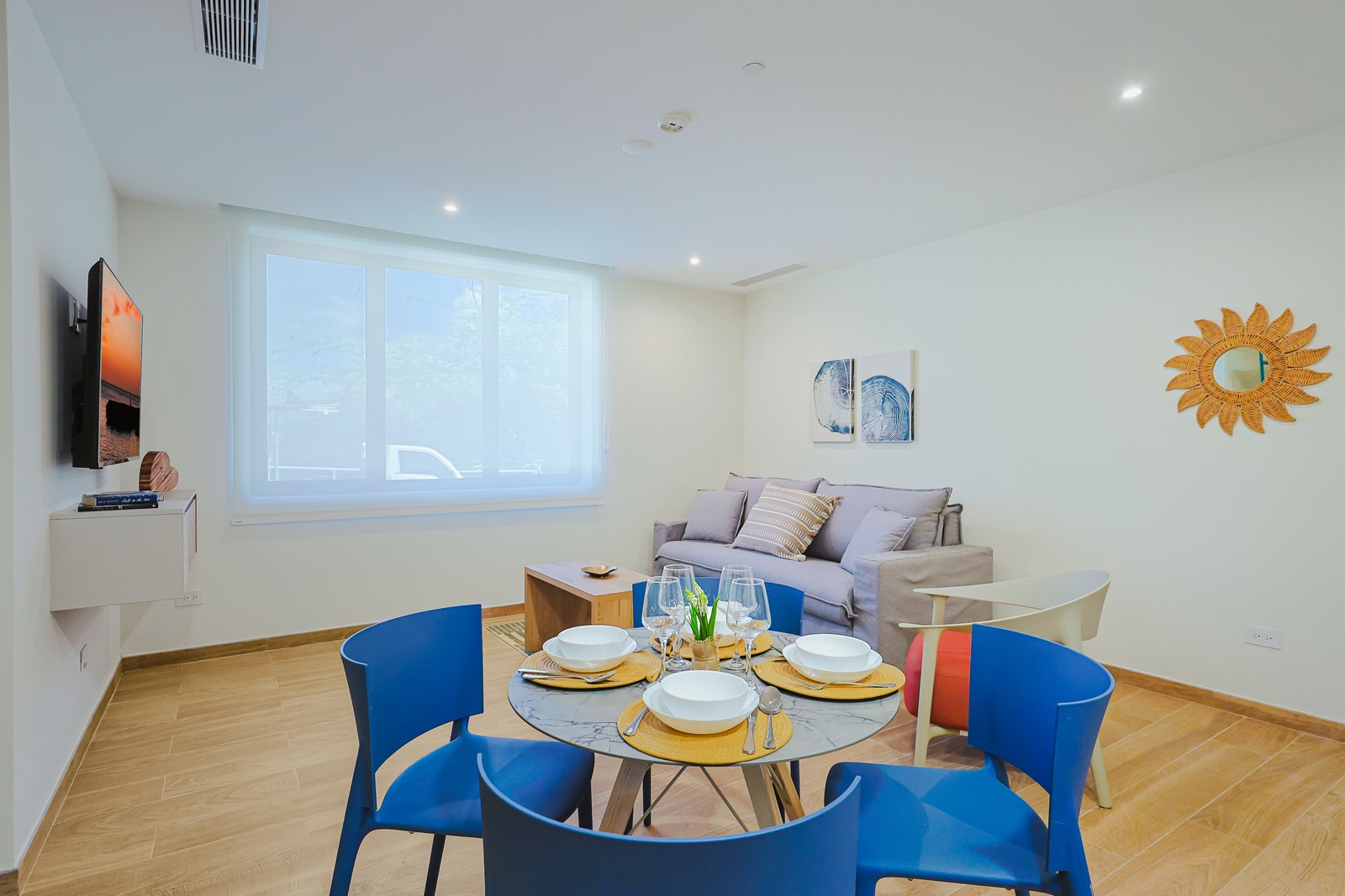 Settle into your bright, open living space where warm wood floors and cheerful pops of blue invite you to relax or gather around the table for a meal together.