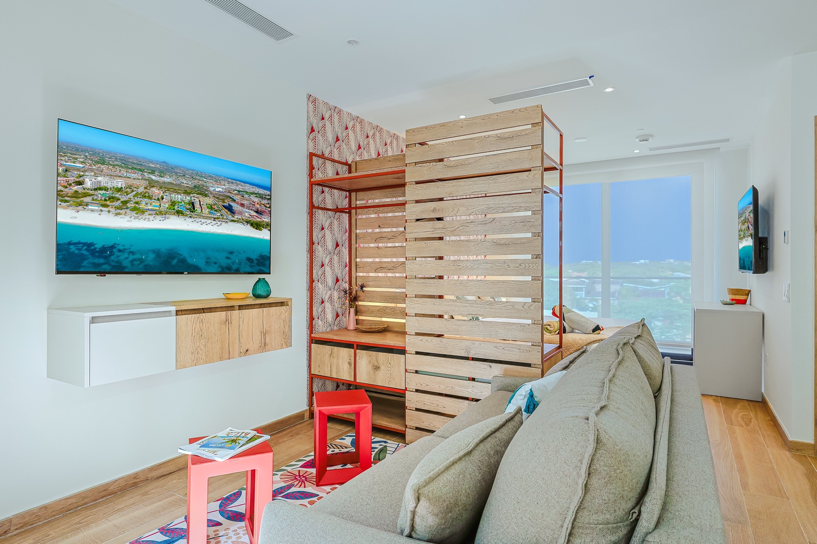A bright and inviting retreat featuring floor-to-ceiling windows that fill the space with natural light. A stylish wooden room divider creates a sense of separation while maintaining the open layout, complemented by a cozy lounge area that's perfect for r