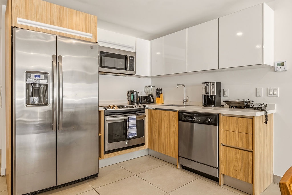 Your modern kitchen is fully equipped with stainless steel appliances, including a fridge with water dispenser, stove, dishwasher, and microwave—everything you need for cooking or reheating after a day of exploring.