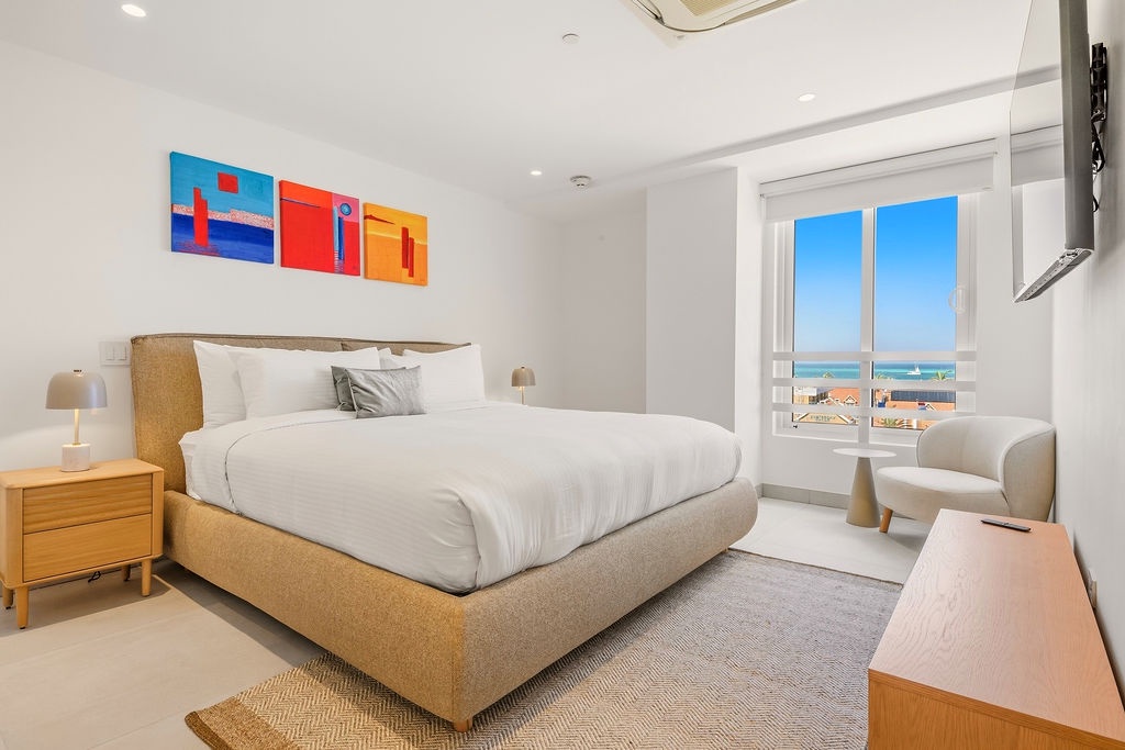 Wake up to stunning beach views right from your bed. This bright, modern bedroom invites you to unwind in crisp linens while the ocean breeze drifts through your window, making every morning feel like a getaway.
