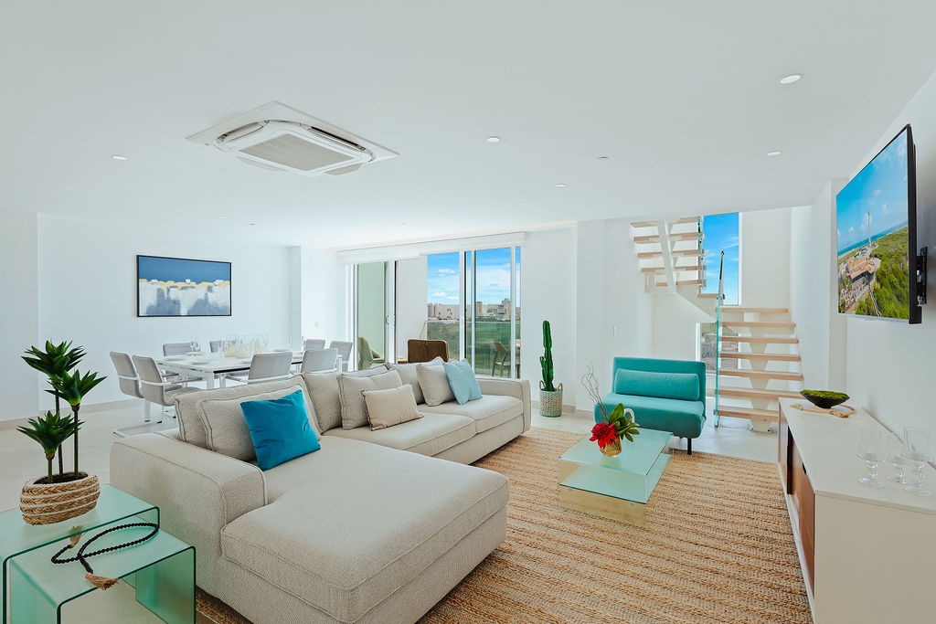 Spacious living area with soaring ceilings, bright windows, and airy design invites you to relax in style. Your coastal retreat awaits with vibrant pops of color and comfortable seating.