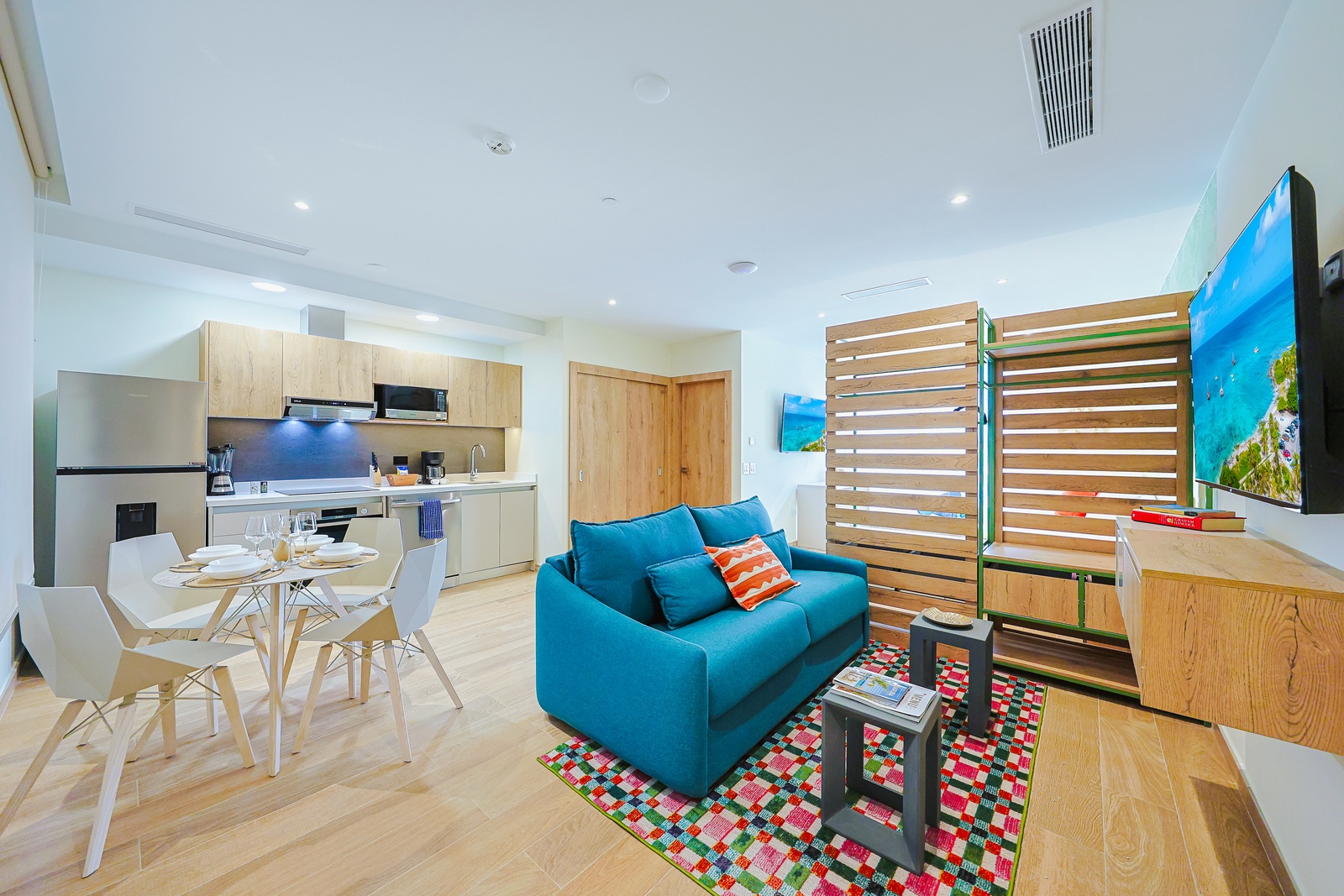 Your bright, open-plan space blends style and comfort with cheerful blue furnishings, warm wood finishes, and a fully equipped kitchen ready for your stay.