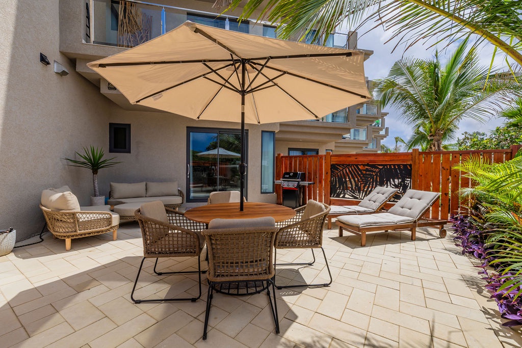 Your private patio is an oasis designed for relaxation, complete with shaded dining, a cozy lounge, sun loungers beneath swaying palms, and a BBQ for easy outdoor meals.