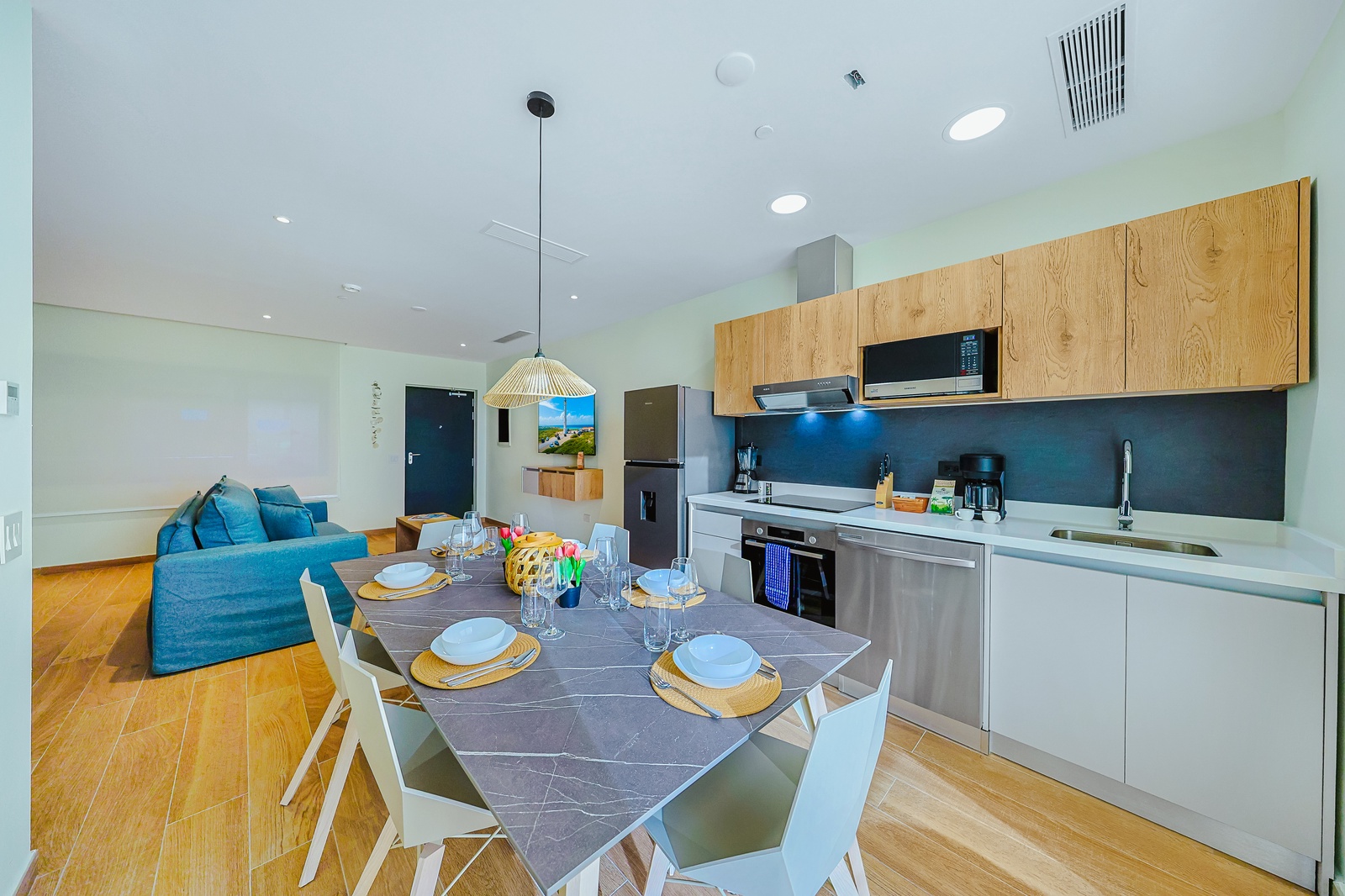 Your open-concept kitchen and living space invites you to gather, cook, and relax in one bright, airy flow, with sleek modern finishes and a dining table ready for shared meals.