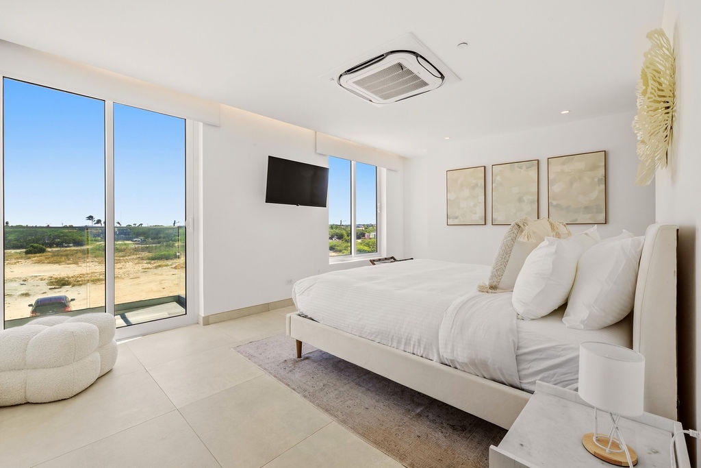 Sink into crisp white bedding and wake to sunshine streaming through floor-to-ceiling windows. Your modern retreat features plush seating and a serene, minimalist vibe—perfect for unwinding after a day of adventure.