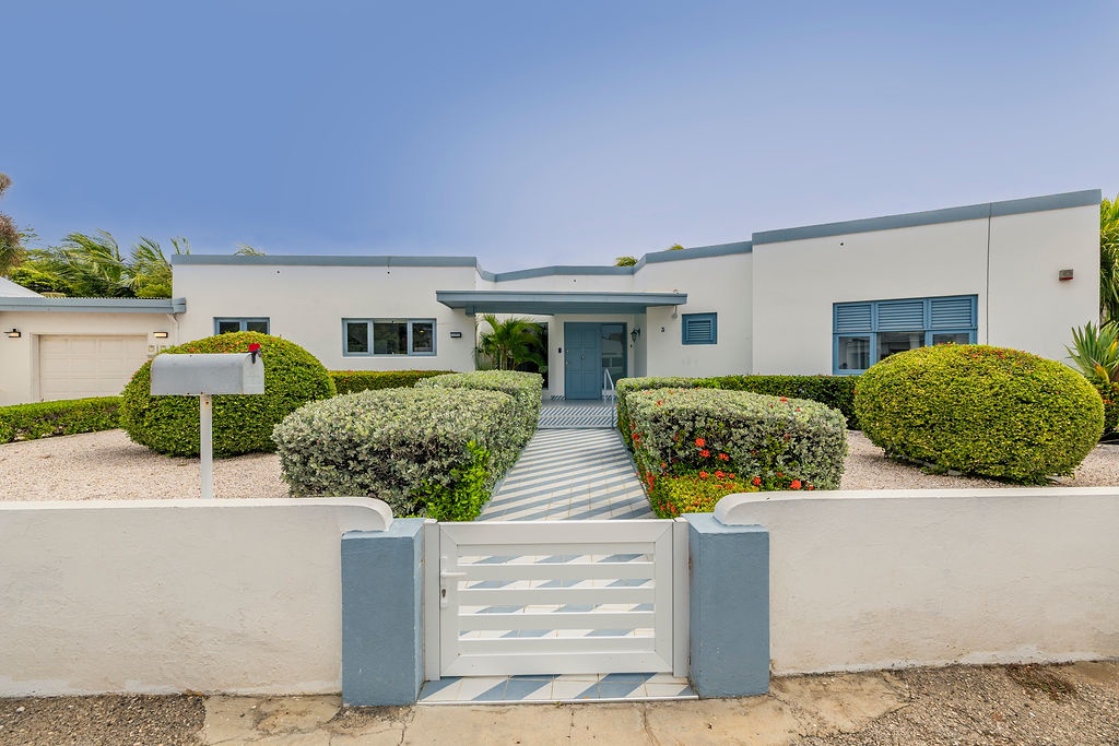 Modern single-story vacation home with landscaped garden and gated entrance, set in a sunny coastal area perfect for relaxed getaways.