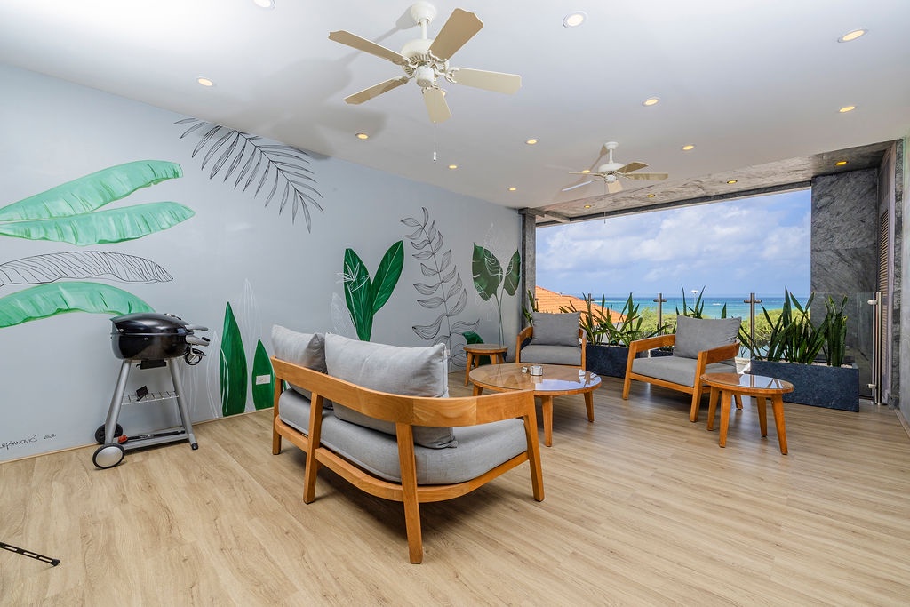 Kick back in your private lounge with playful tropical murals, stylish mid-century seating, and an open-air terrace framing stunning ocean views.
