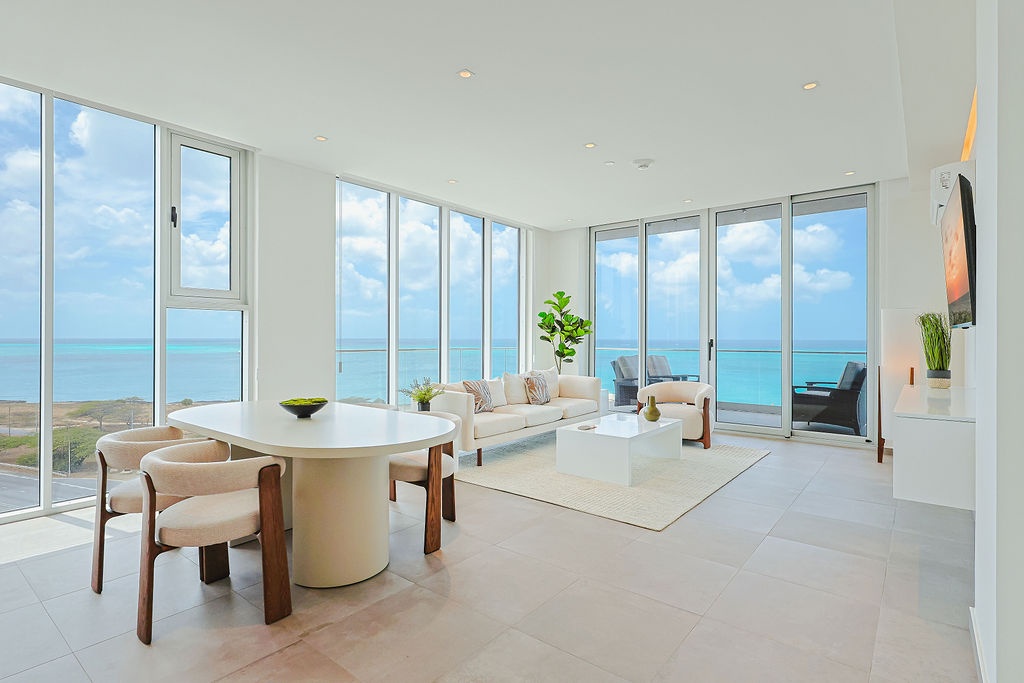Your oceanfront sanctuary features floor-to-ceiling windows framing endless turquoise waters, creating a seamless indoor-outdoor living experience.