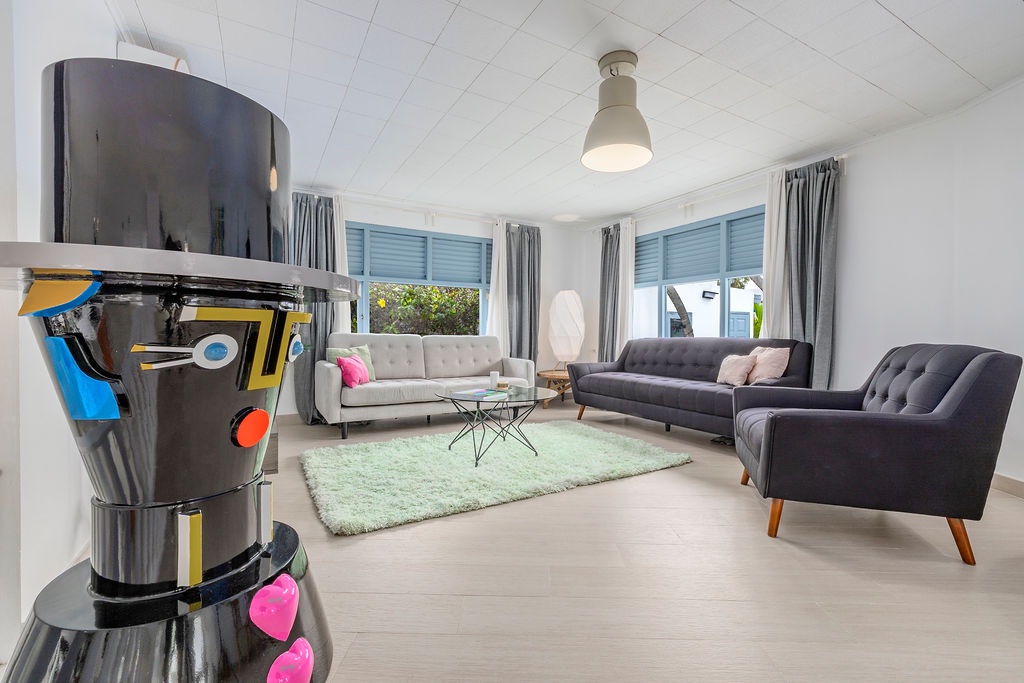 Unwind in your sun-filled living room, where three plush sofas invite you to relax after a day of exploring. Bright windows frame garden views, and every detail feels thoughtfully arranged for your comfort.