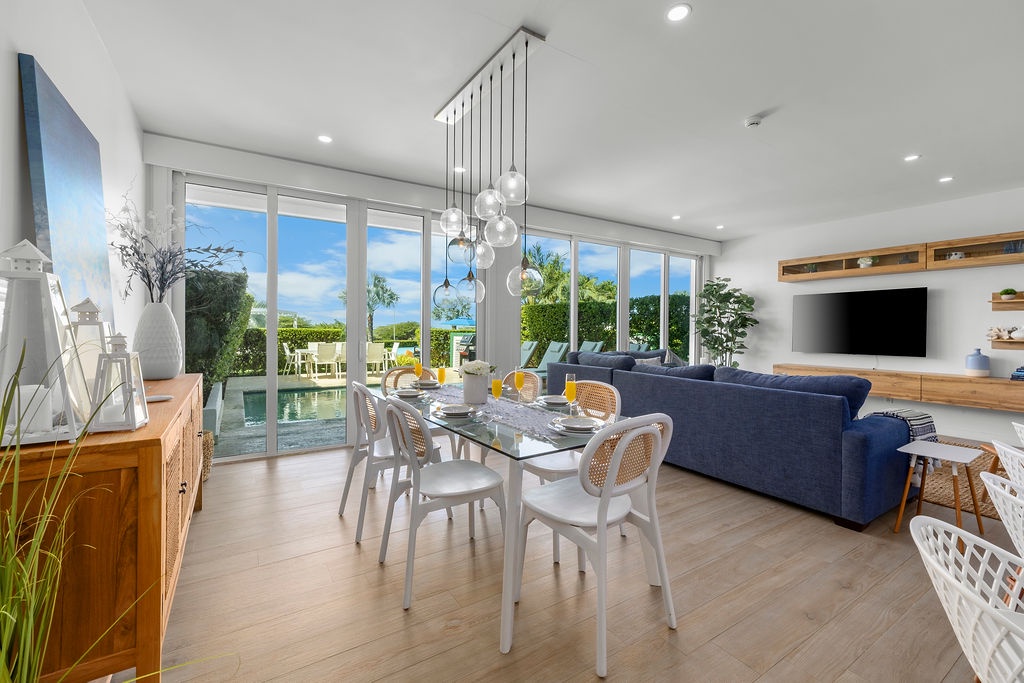 Gather around your elegant dining table with panoramic garden views streaming through floor-to-ceiling windows in this bright, open living space.