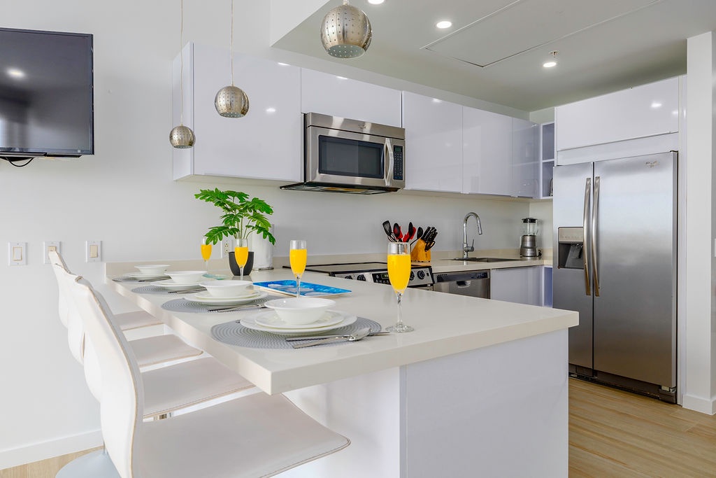 Your sleek modern kitchen awaits with stylish pendant lighting, stainless steel appliances, and a breakfast island ready for morning mimosas.