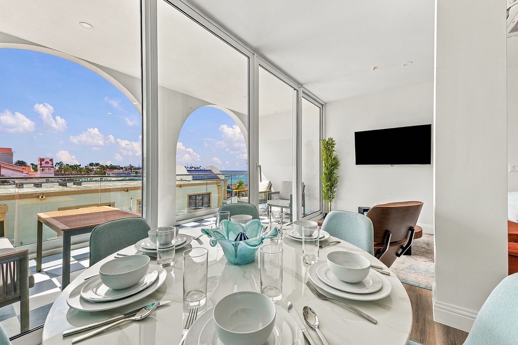 Gather around your elegant dining table with waterfront views framing your meals. Natural light floods the space through expansive glass doors, while the balcony beckons you to savor morning coffee with a refreshing sea breeze.