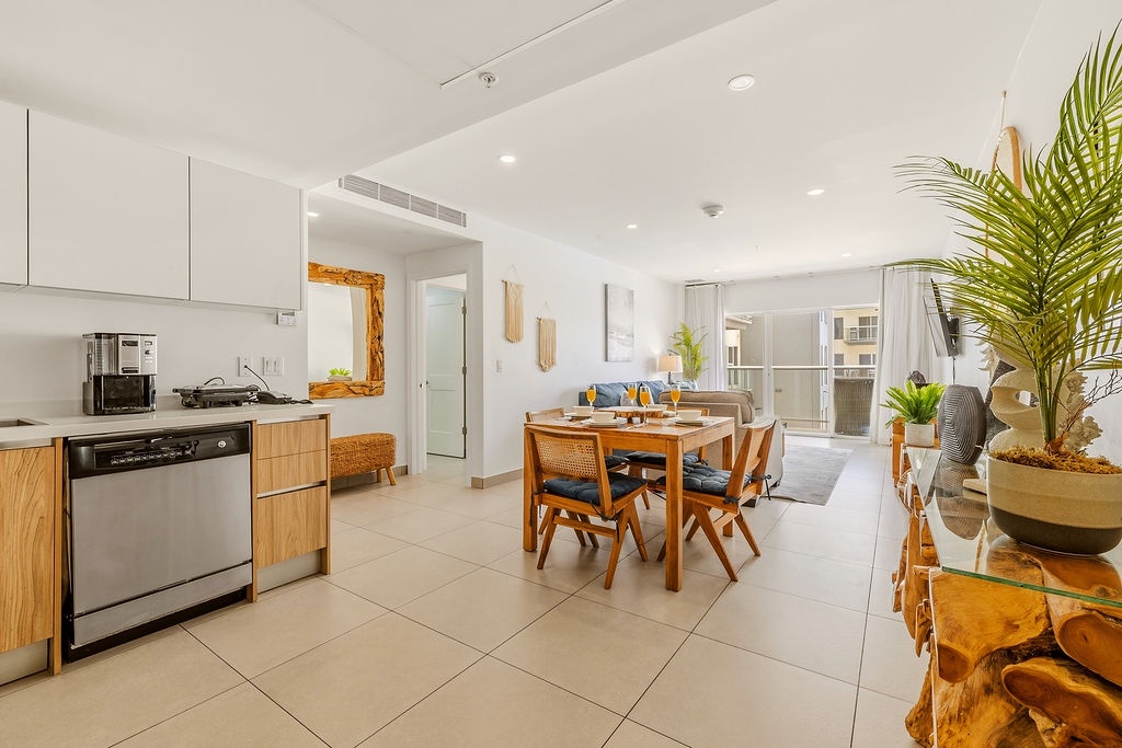Bright, open living awaits, where you'll find a fully-equipped kitchen, inviting dining space, and cozy living area—all flowing seamlessly together under natural light and tropical accents.