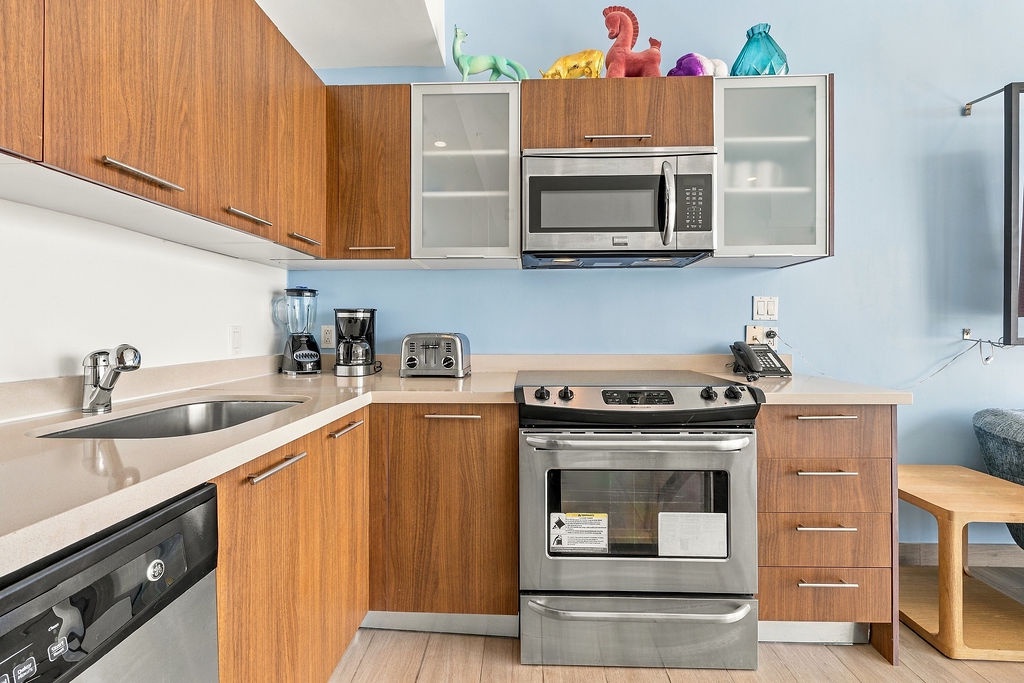 Whip up your favorite meals in this fully equipped kitchen with modern stainless appliances, sleek wood cabinetry, and everything you need to feel right at home.