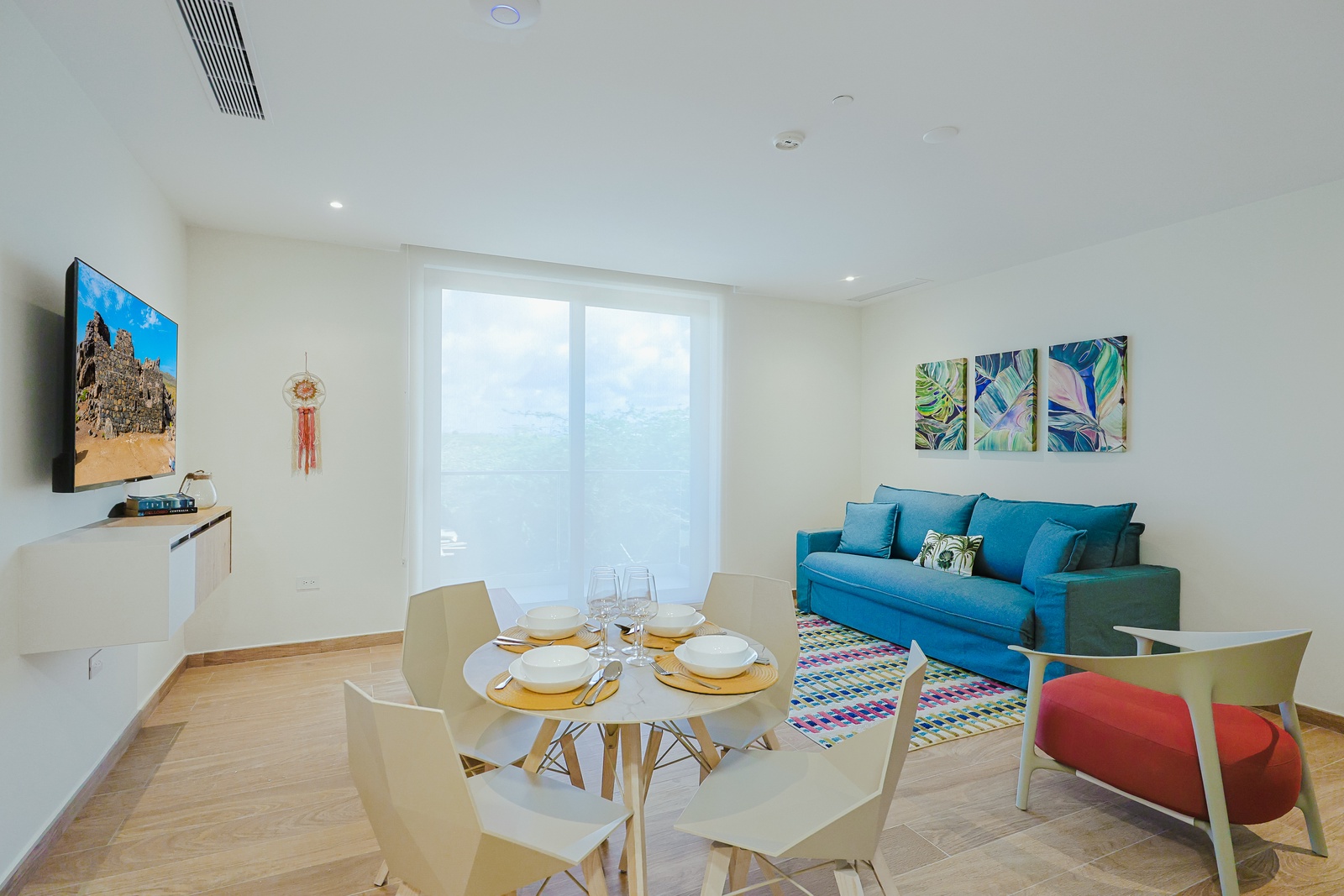 Relax in your bright, open-concept living space where modern comfort meets tropical flair. Settle into the cozy sofa, share meals at the stylish round table, and enjoy your favorite shows in a cheerful setting.