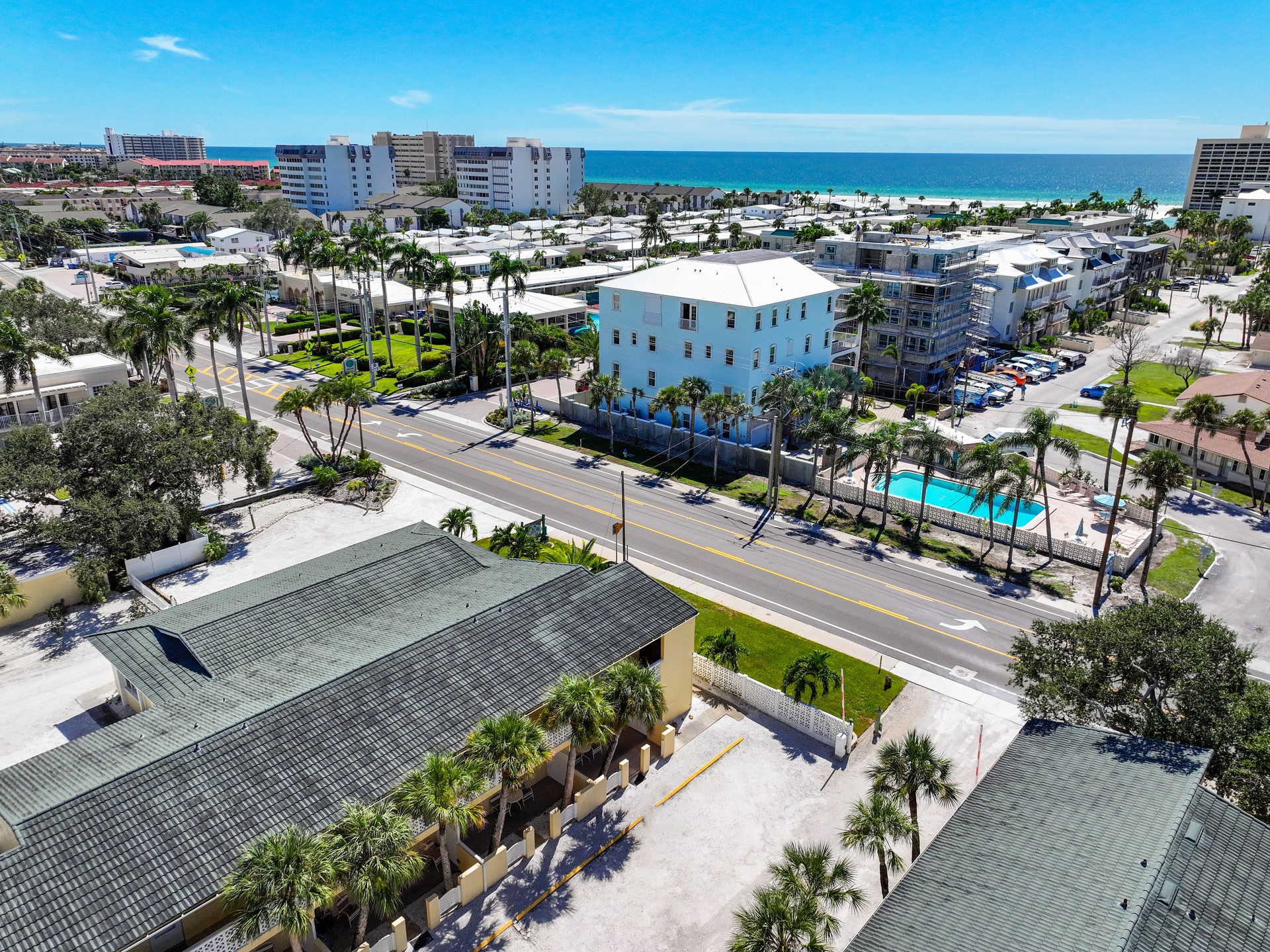 Aerial view of the property nestled in a coastal neighborhood, just steps from the beach and surrounded by palm-lined streets and nearby amenities.