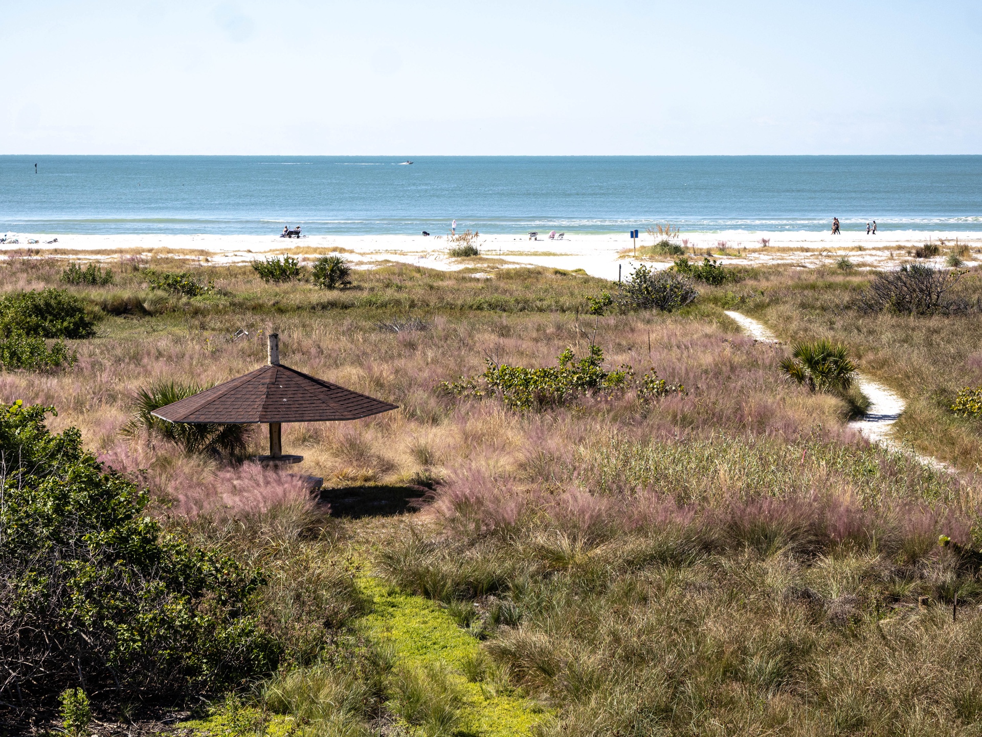 A peaceful coastal property offering direct access to pristine beaches and tranquil ocean views, surrounded by natural dunes and winding pathways.