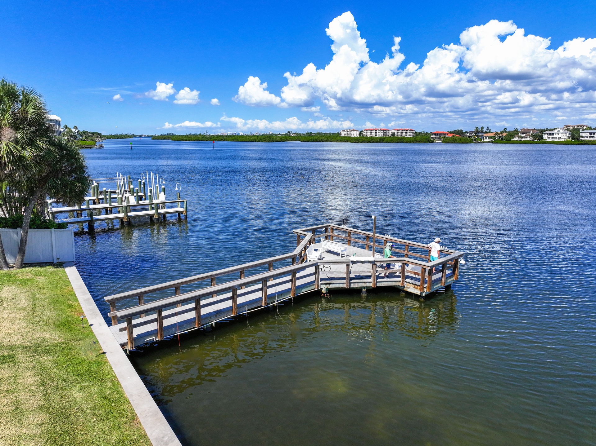 A private dock stretches into calm blue waters, surrounded by tropical palms and expansive waterfront views—perfect for launching kayaks, fishing, or simply soaking in the coastal beauty from your doorstep.