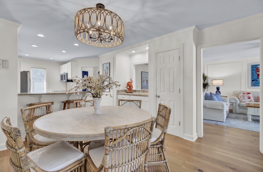 Picture yourself gathering with loved ones around this beautiful round table, warmed by soft lighting and coastal charm. The open flow connects you to the kitchen and living spaces for effortless entertaining.