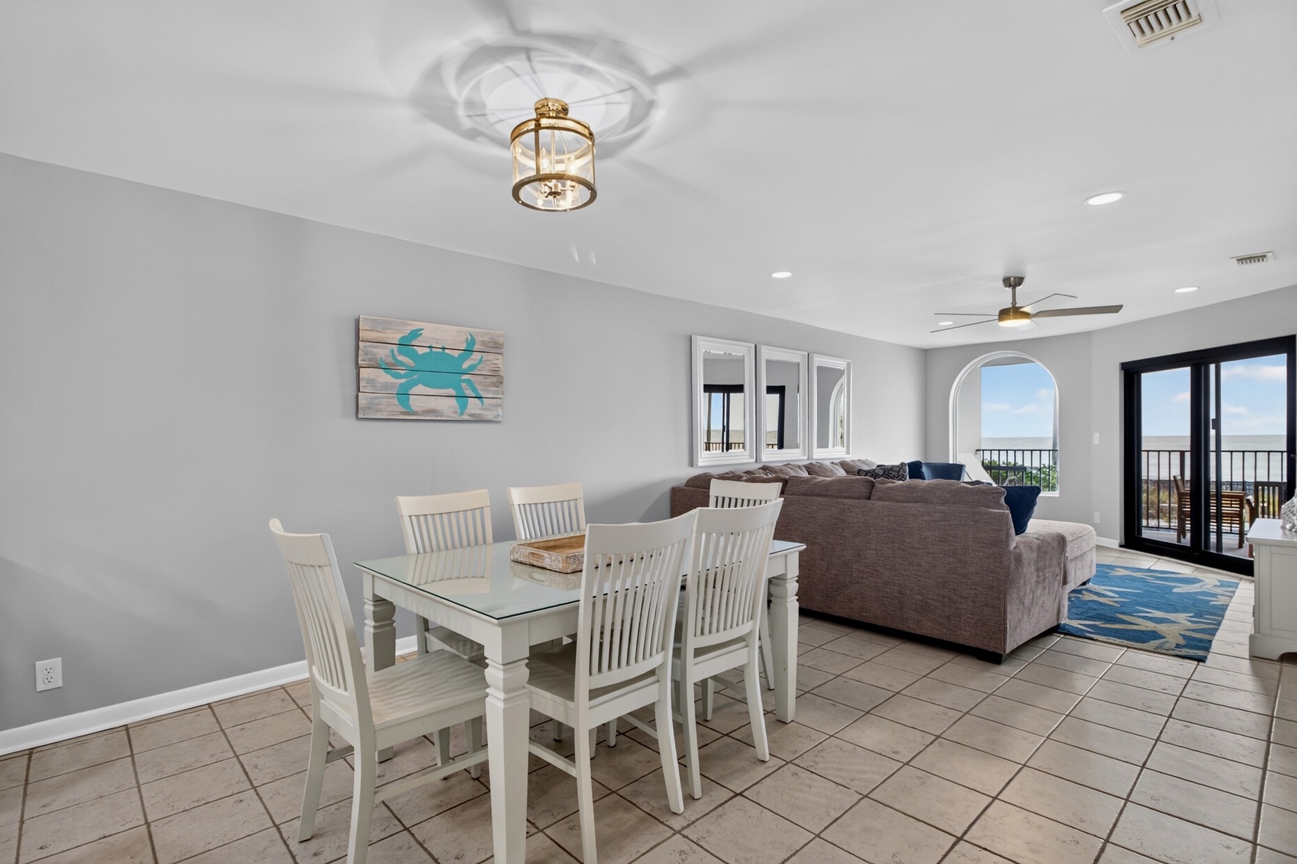 Step into this bright, coastal-inspired living space where you'll find comfortable seating, charming beach decor, and arched doorways framing stunning views. Enjoy meals at your dining table or unwind with ocean breezes from your private balcony.