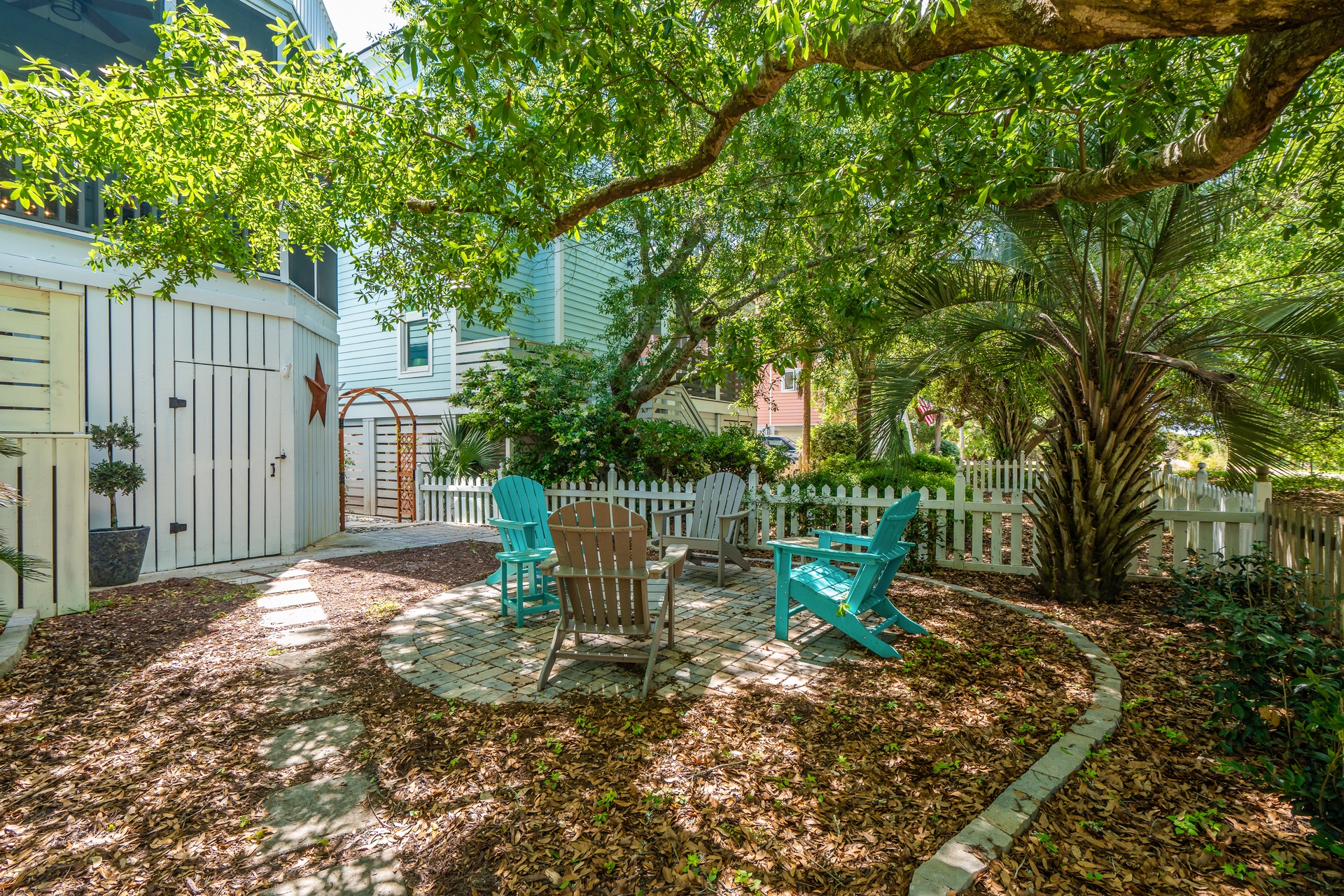 Your private backyard oasis awaits, with colorful Adirondack chairs shaded by mature trees—perfect for morning coffee or an afternoon read.