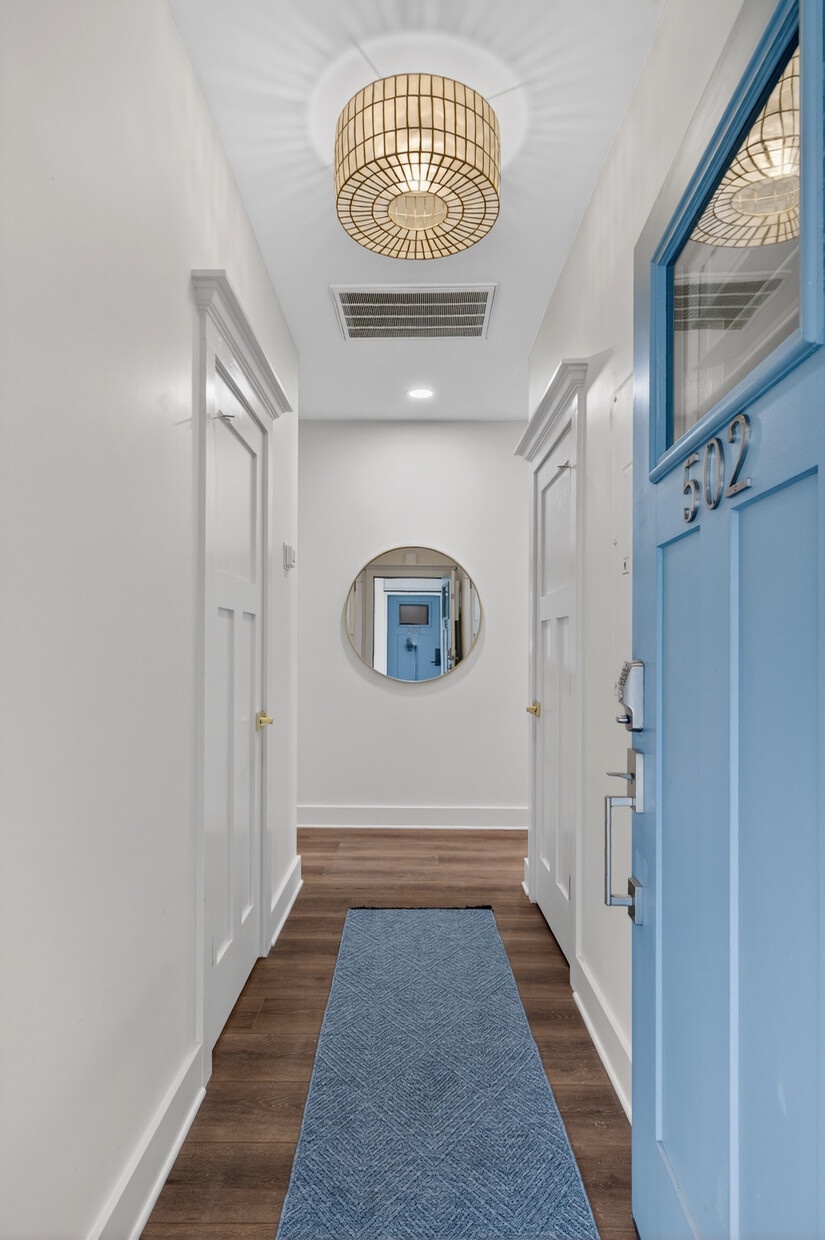 Step into your welcoming hallway with warm wood floors, coastal blue accents, and elegant ceiling lighting creating a serene entrance.