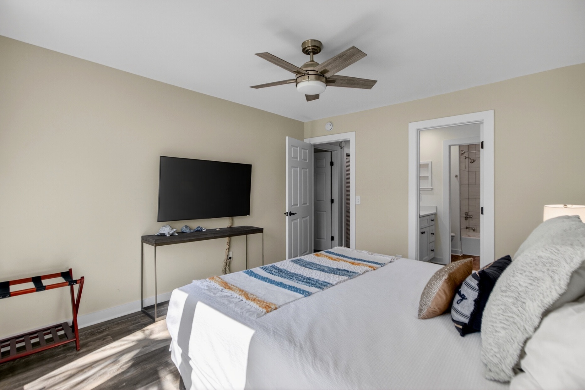Relax in your bright, airy bedroom featuring a ceiling fan and flat-screen TV. The ensuite bathroom is just steps away for your convenience.