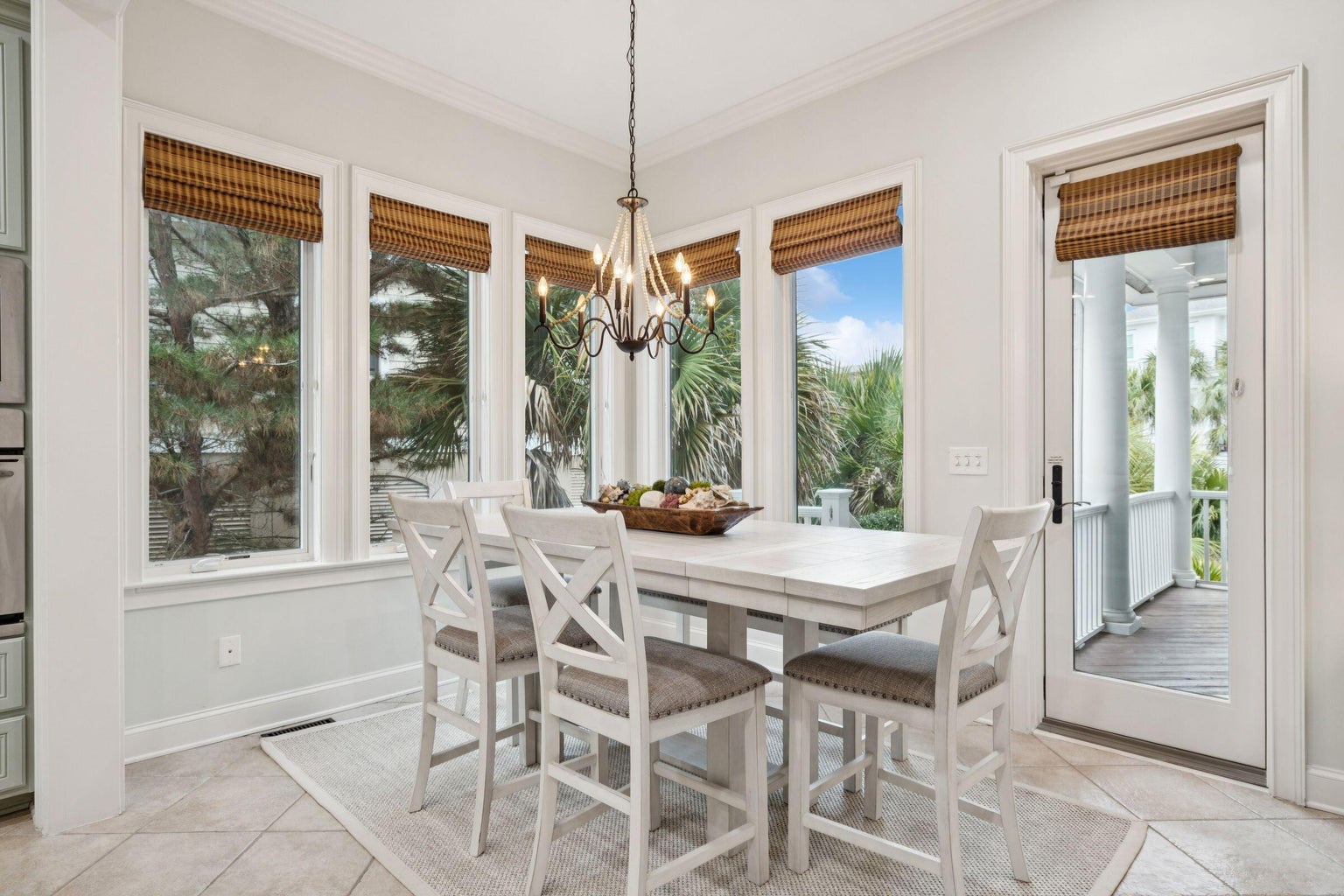 Gather around this bright dining nook where bamboo shades filter gentle light and tropical views create your perfect breakfast backdrop.