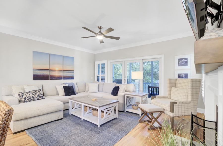 Relax in your stylish living room with plush seating, coastal artwork, and peaceful views through French doors to your private balcony.