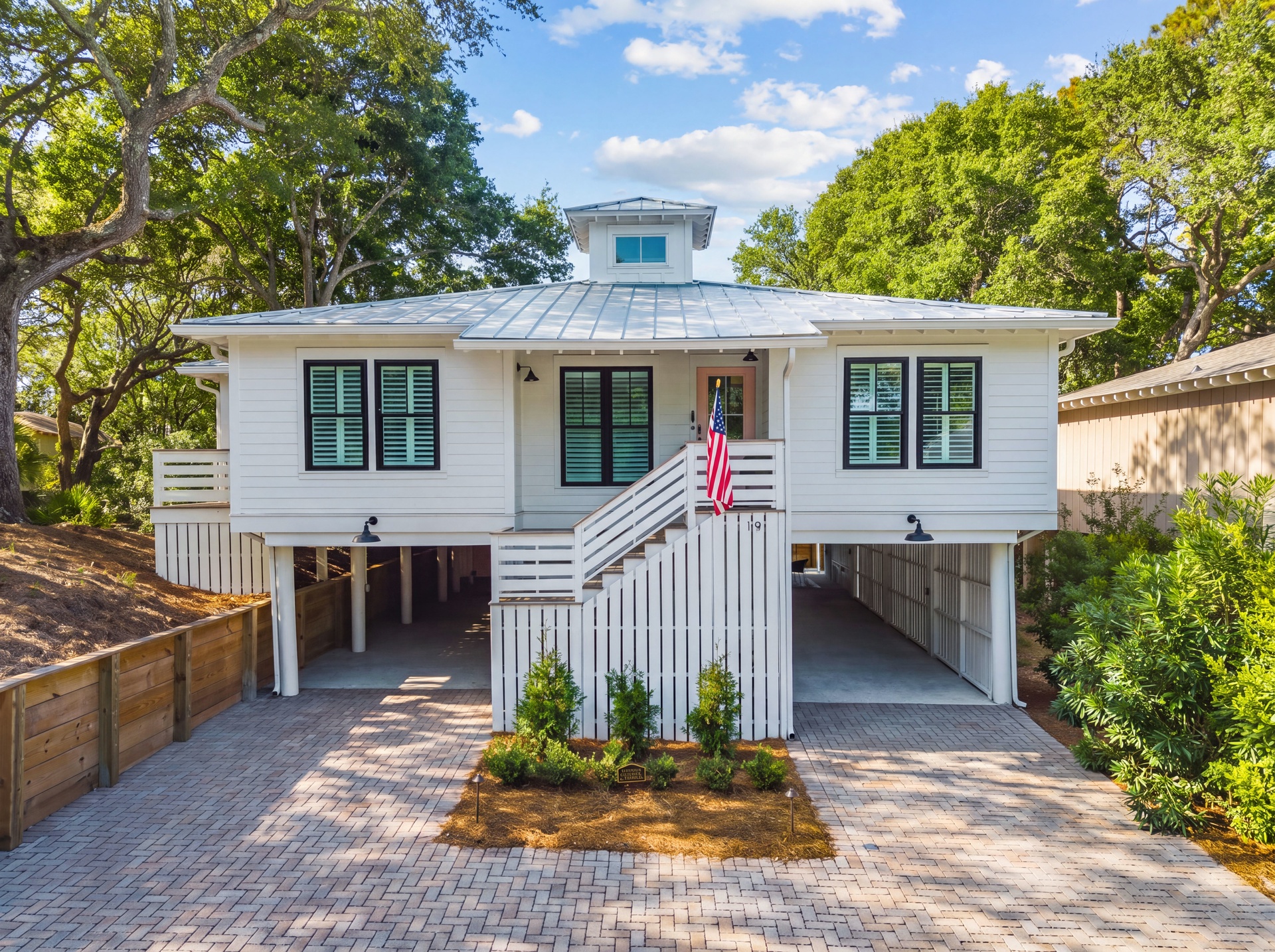 Charming coastal cottage with elevated design, nestled among mature oak trees with convenient covered parking and welcoming front porch entrance.