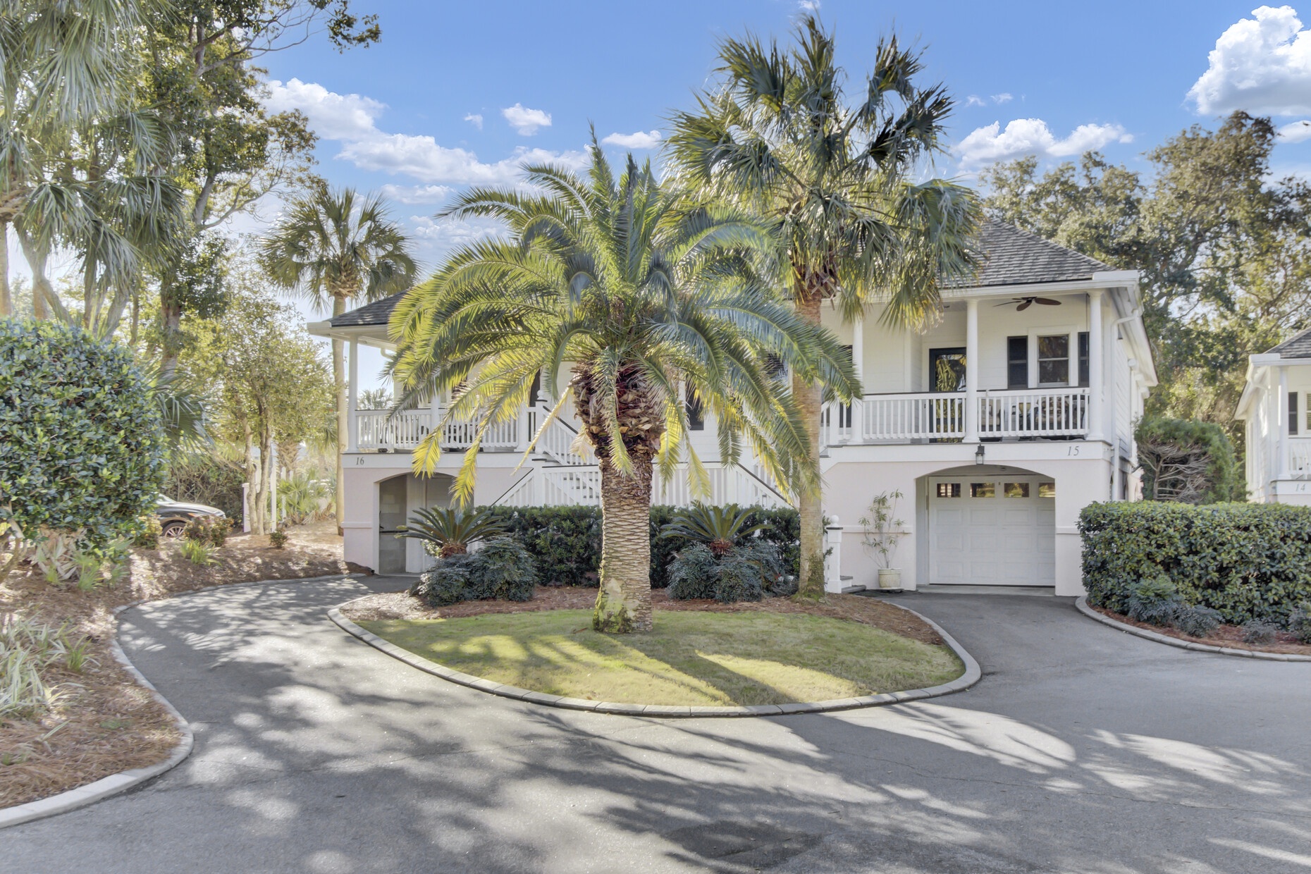 Charming coastal home with palm-lined driveway and tropical landscaping in a peaceful residential setting.