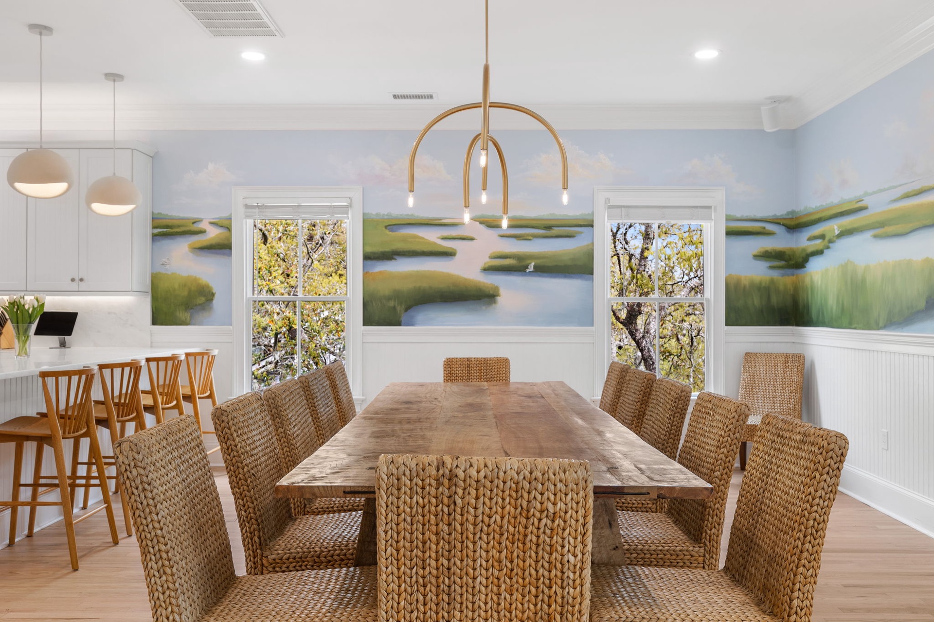 Gather around your dining table under modern lighting while beautiful marshland artwork creates a serene backdrop for memorable meals together.